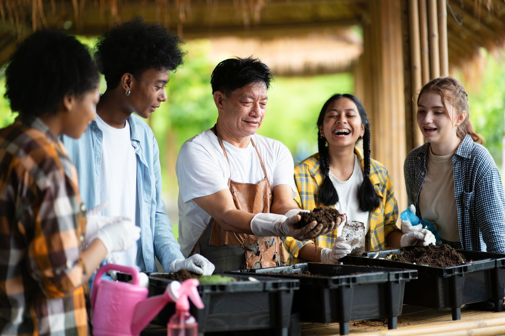 Friends laughing around a picnic grill, serving food at an outdoor gathering
