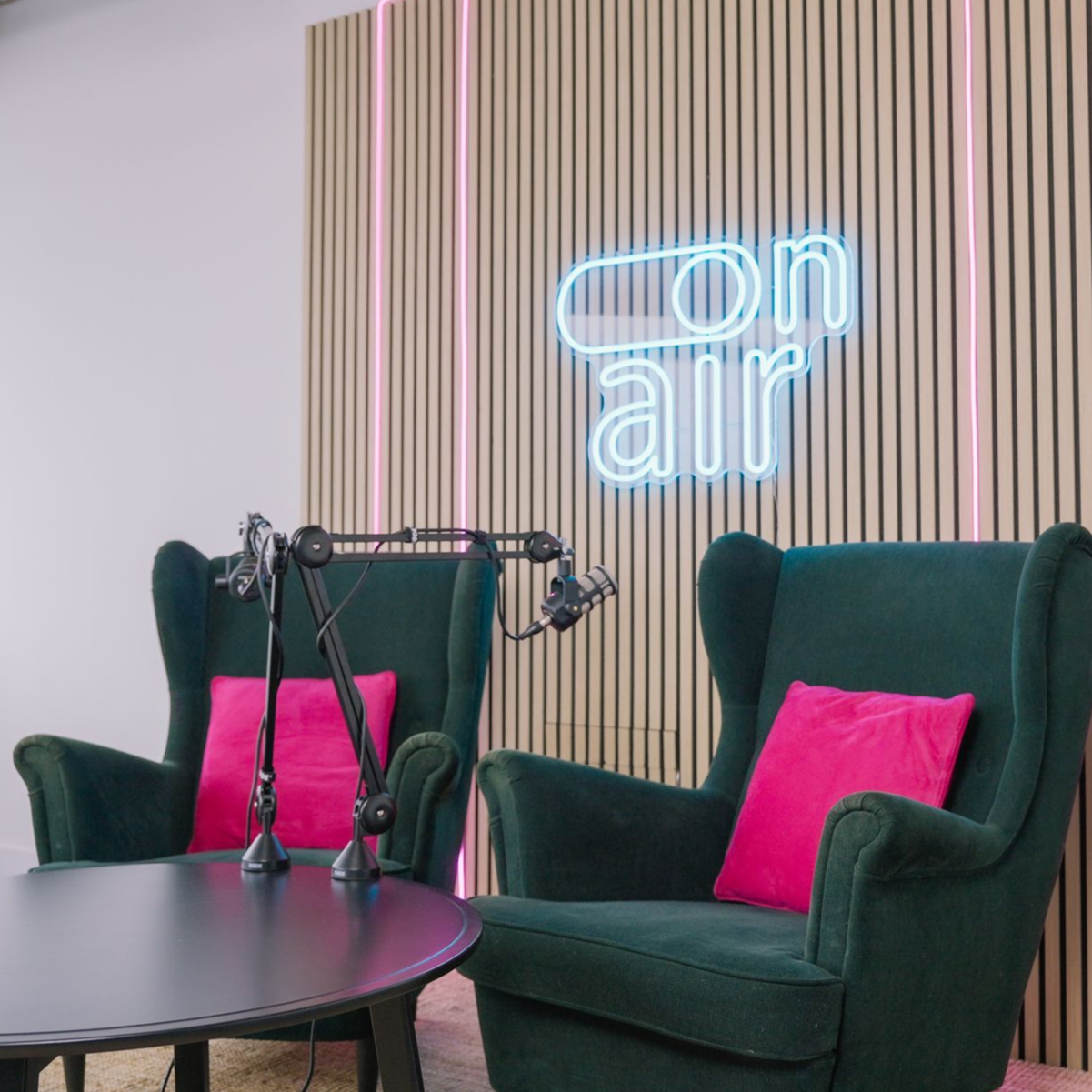 B1 Studios podcast set with chairs, table, microphones and neon backdrop
