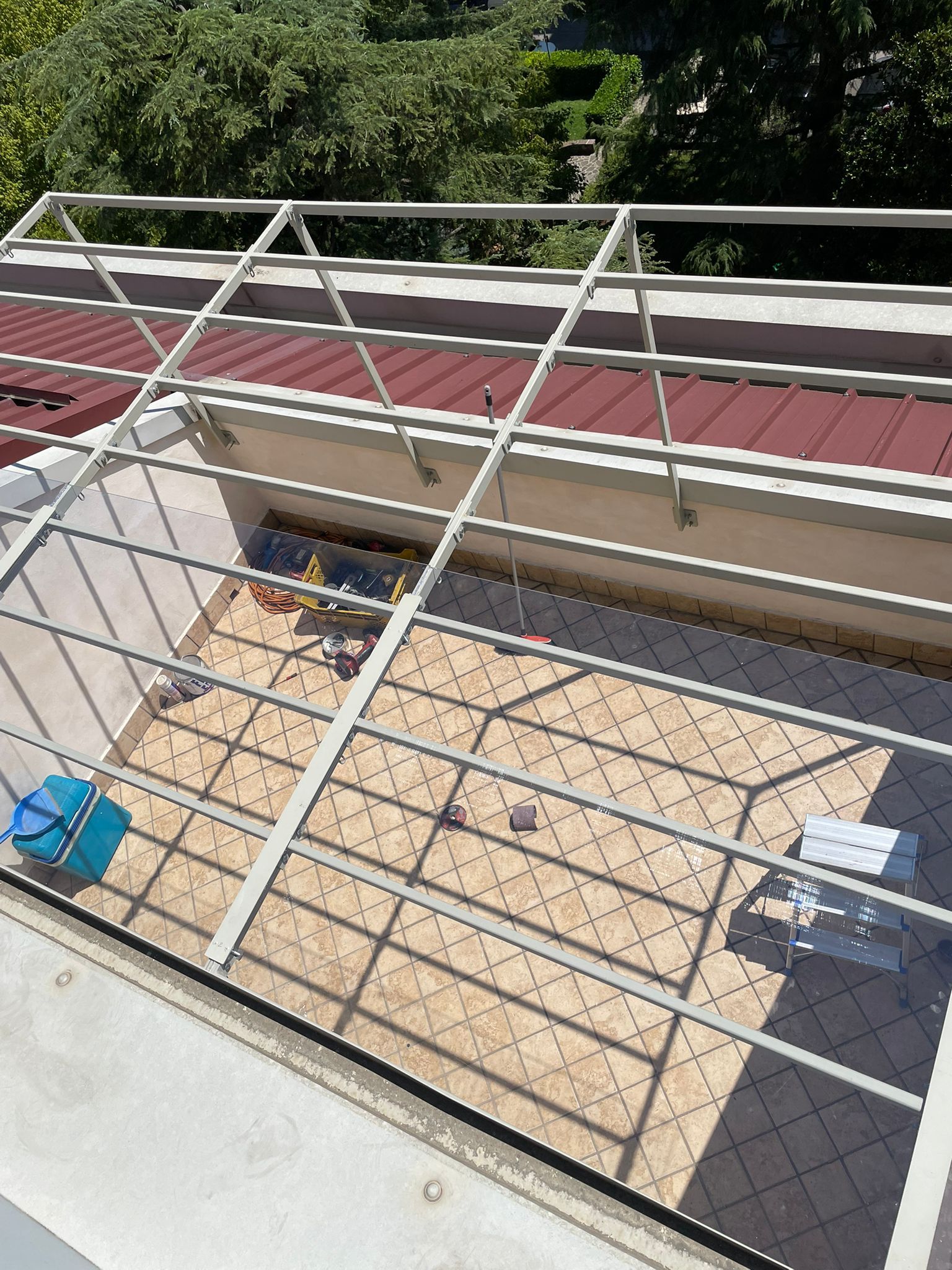 Terrazza sul tetto con ringhiera in metallo, pannelli del tetto rossi e pavimento piastrellato beige in piena luce del sole