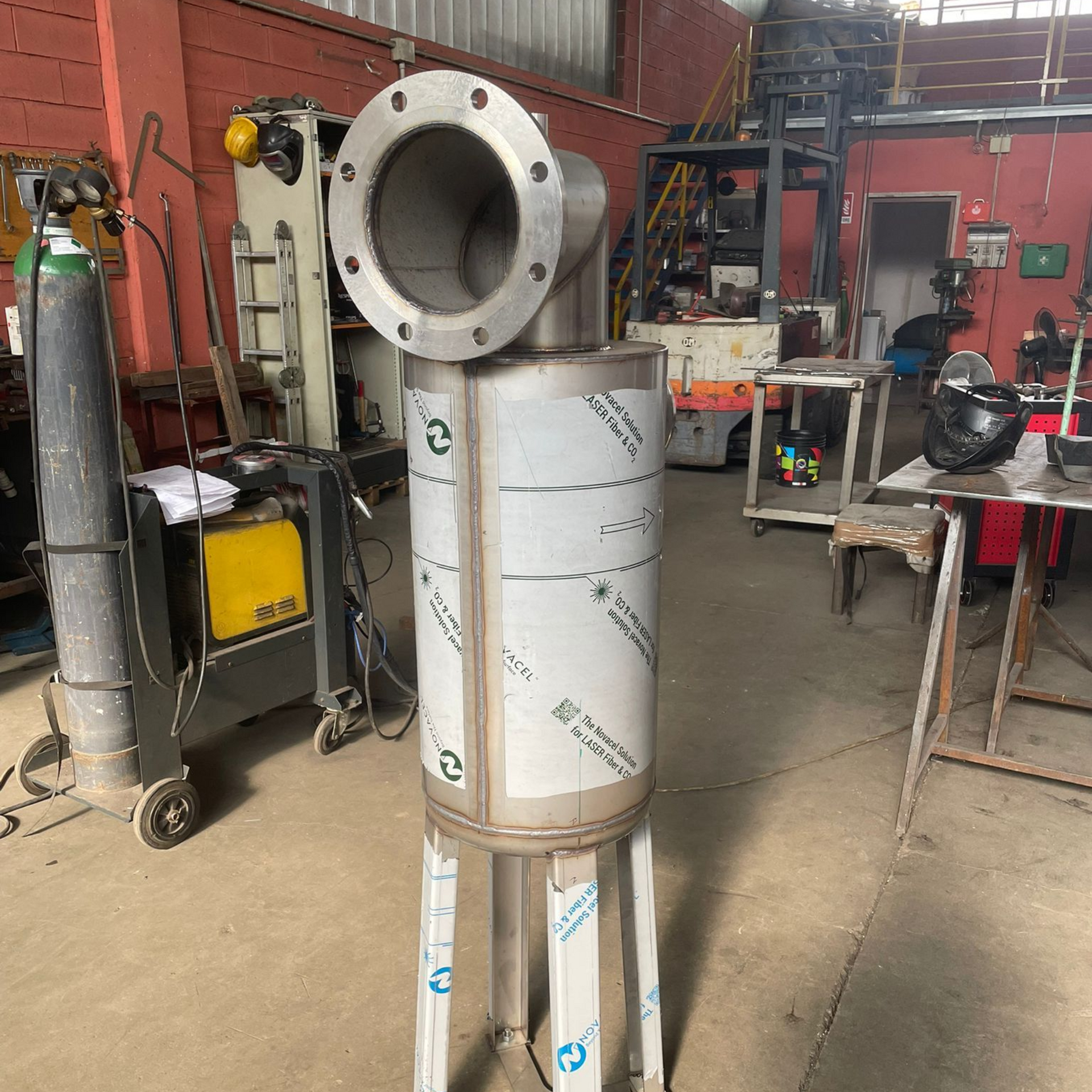 Assemblaggio di condotto metallico con ampia flangia circolare su un supporto in un'officina.