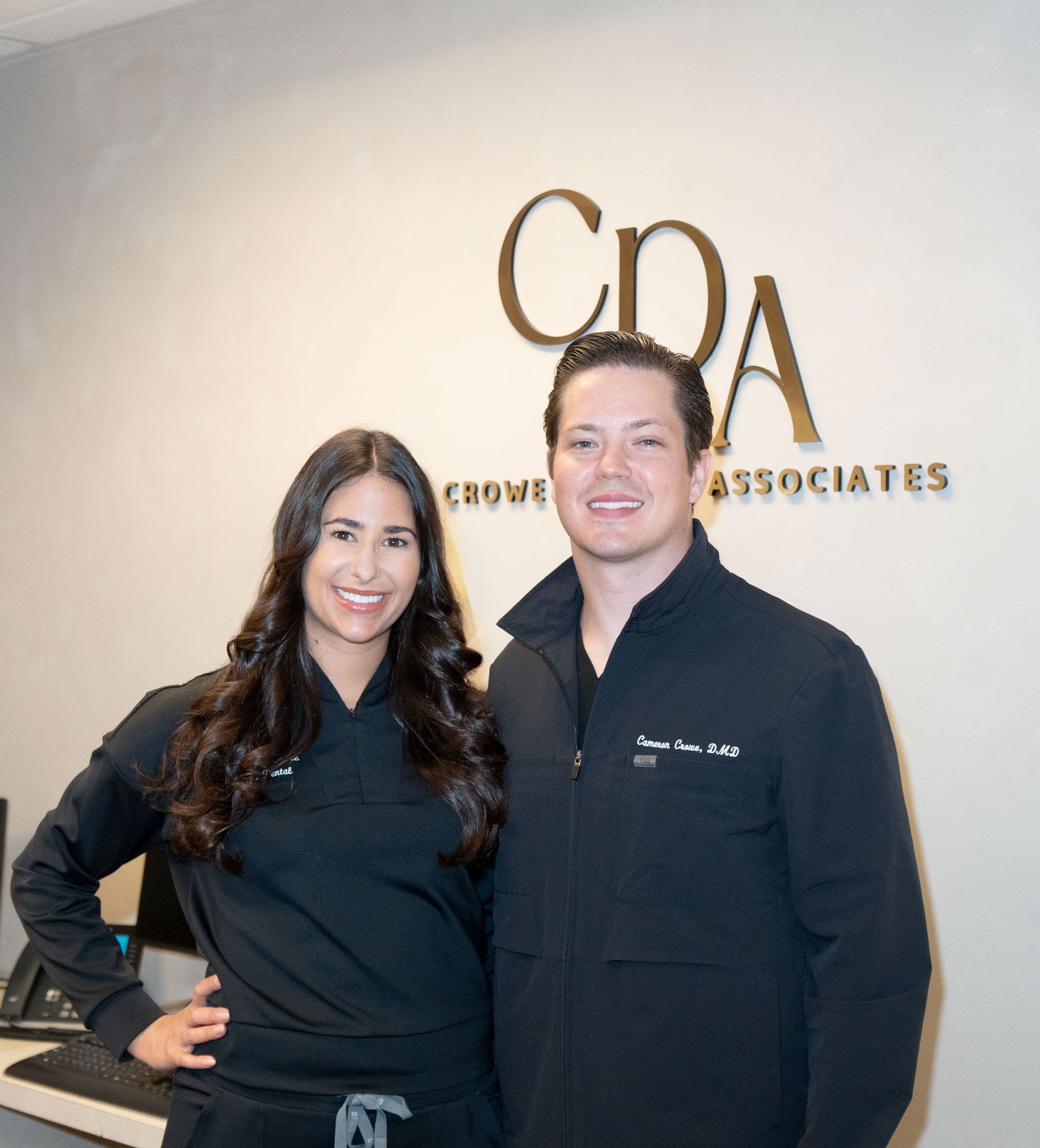 Two people smiling in black shirts standing in front of a CPA Associates sign.