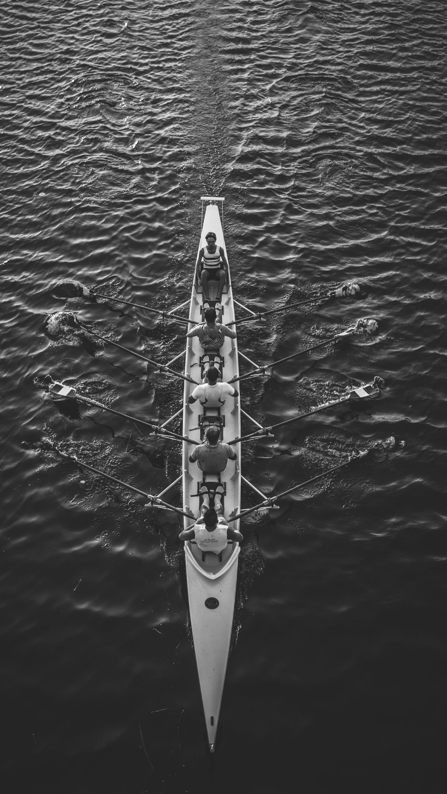 Equipe de remo em um corpo d'água, vista diretamente de cima.