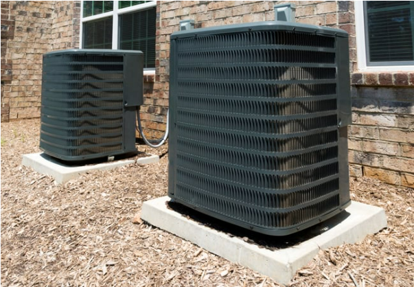 Two air conditioners are sitting outside of a brick building. Two air conditioners are sitting outside of a brick building.