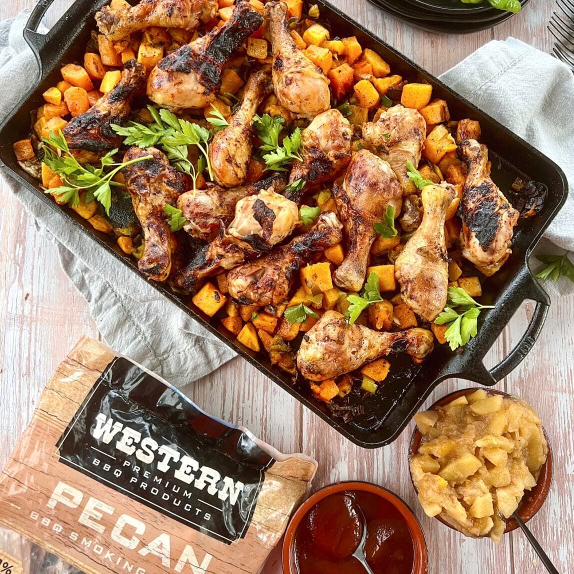 Smoked chicken drumsticks on a bed of grilled butternut squash with a bag of Western Pecan Smoking Chips