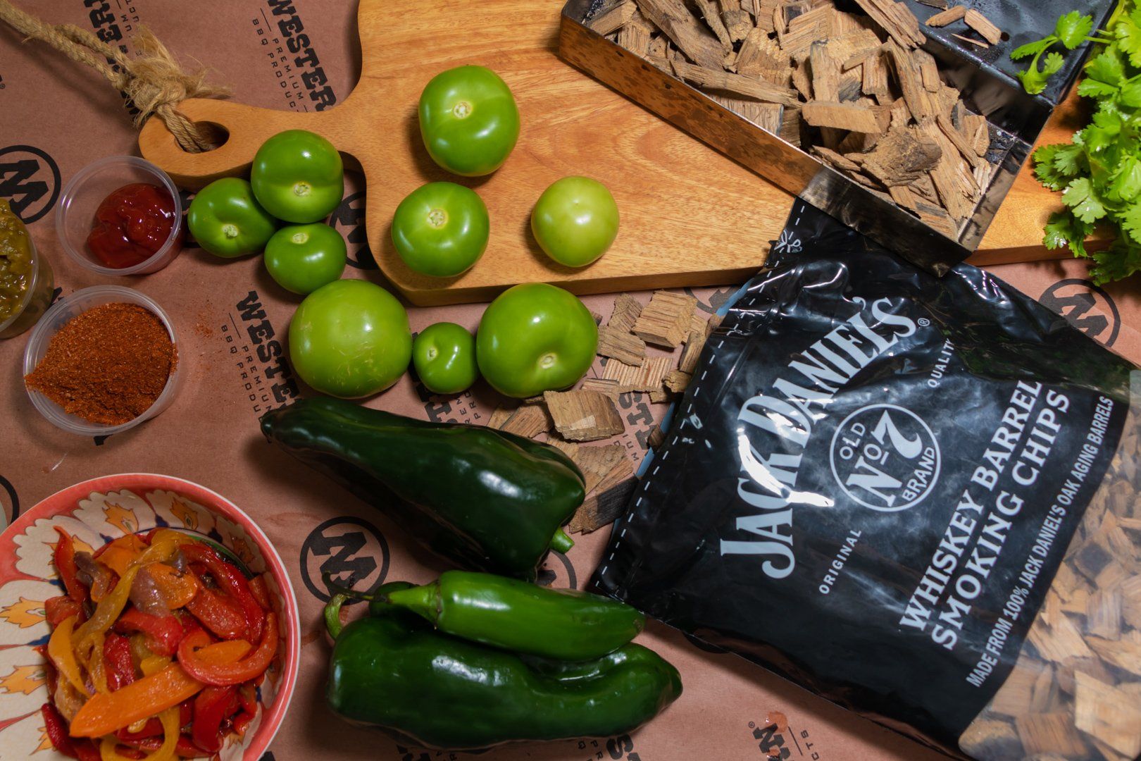 Birds eye view of Jack Daniels Whiskey Barrel chips bag, loose chips in smoker and peppers