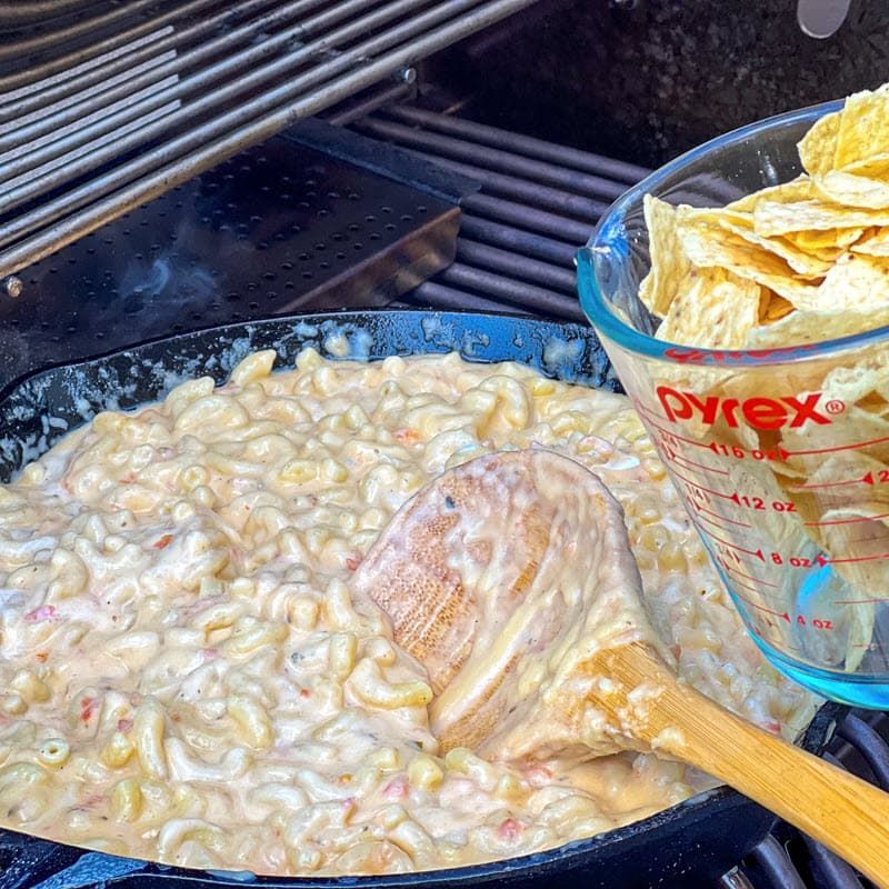 closeup of pecan smoked salsa mac and cheese on the grill with a cup of tortilla chips next to it