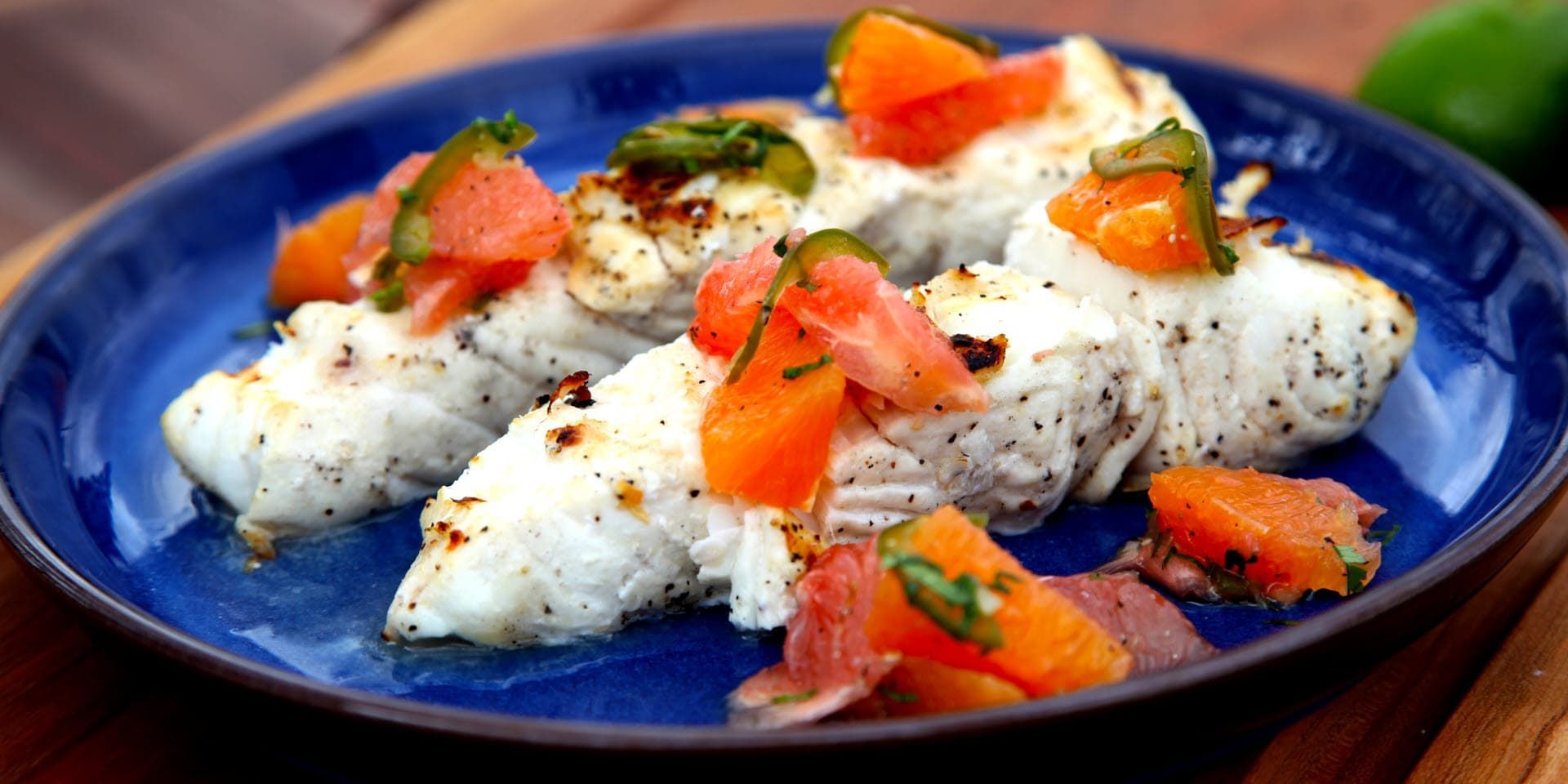 grilled mahi mahi fillets topped with diced tomatoes and herbs on a blue plate