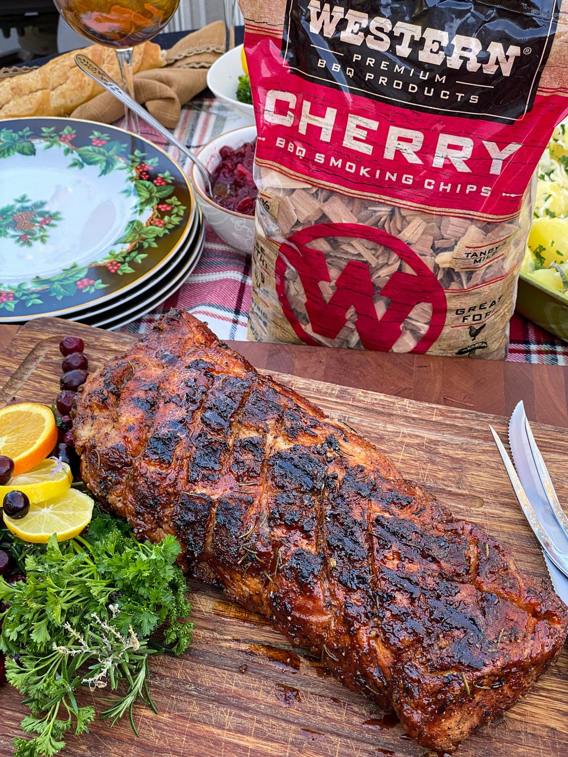 Whole smoked pork loin with garnish and cherry chips bag in background