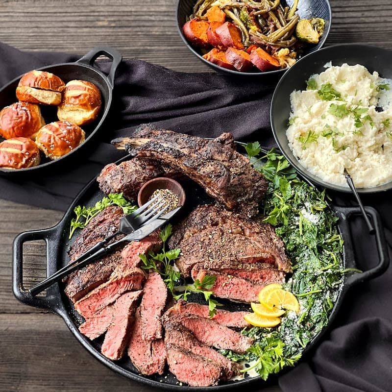 Grilled Sliced Ribeye with mashed potatoes, dinner rolls and vegetables