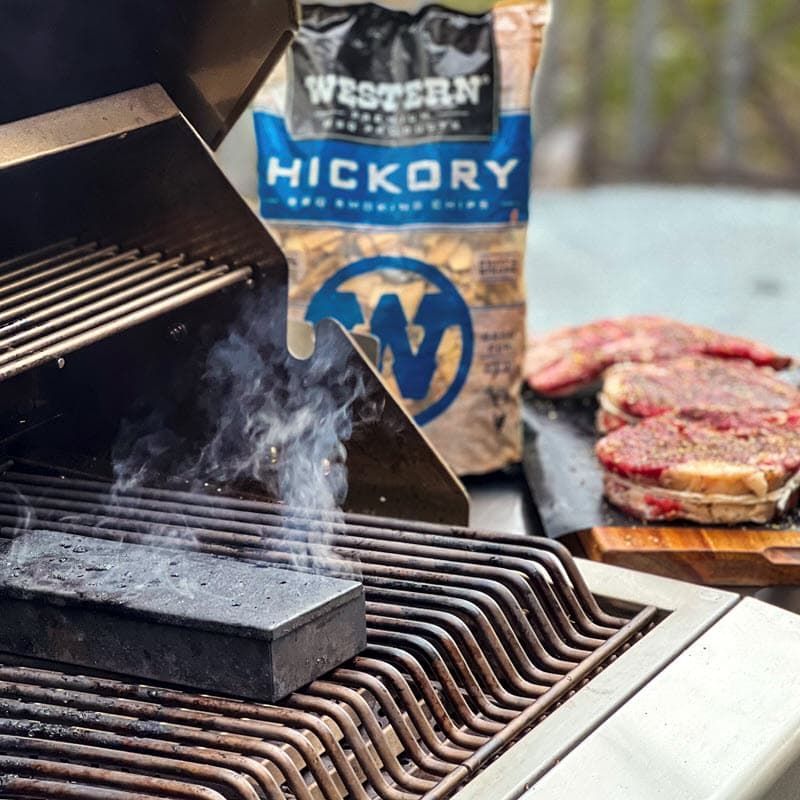 Smokebox smoking on grill with bag of Hickory Chips and raw cut ribeye in the background