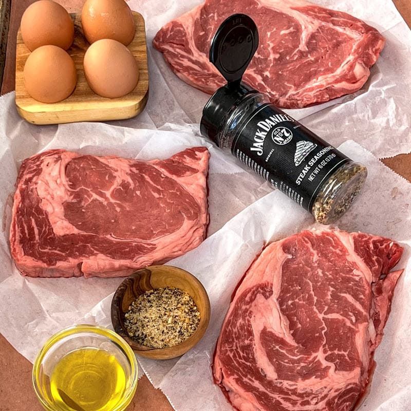 Raw steaks, eggs, oil, pepper & Jack Daniel's® Steak Seasoning
