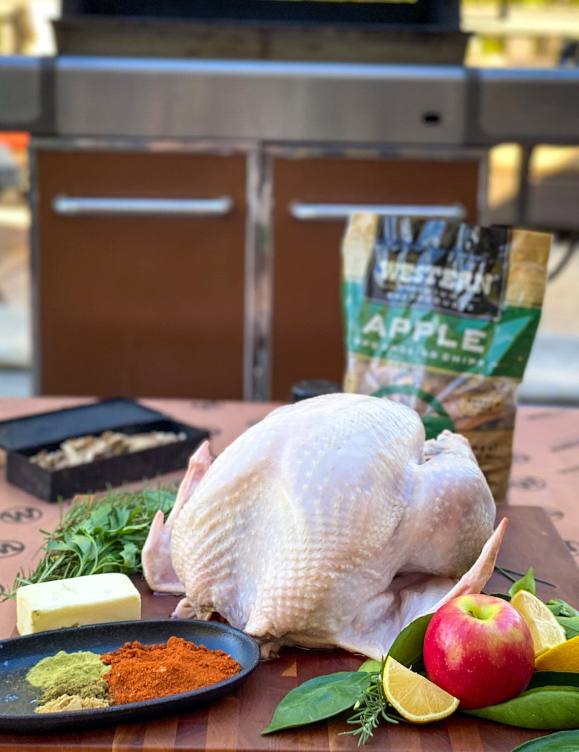 Whole uncooked turkey with butter, spices, apple and other ingredients with bag of Western Apple Smoking chips