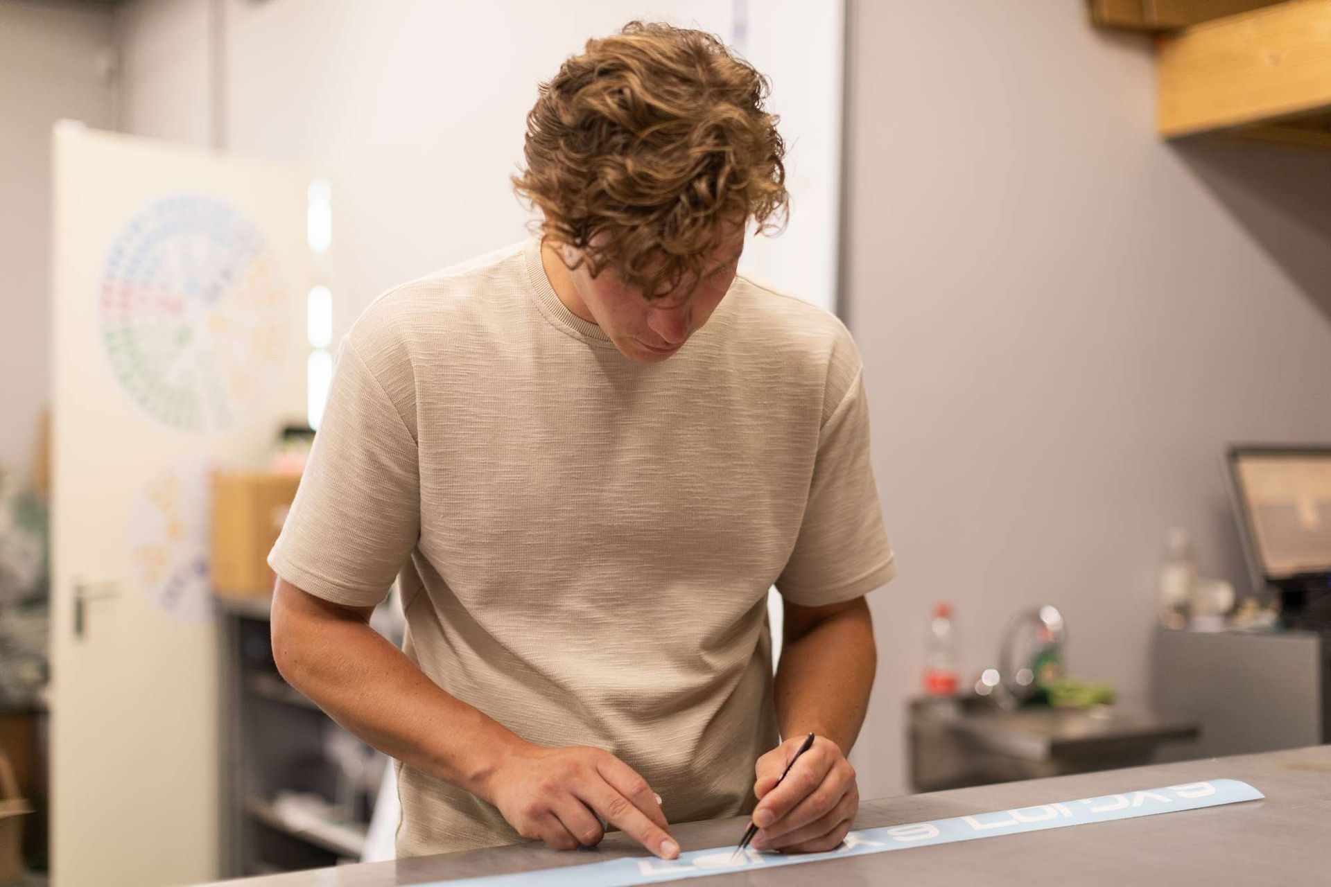 Een man staat aan een tafel en tekent op een stuk papier.