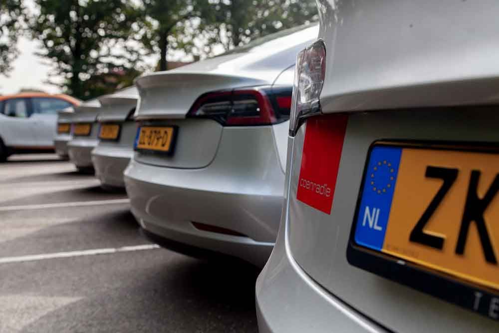 Een rij Tesla-auto's staat geparkeerd op een parkeerplaats.