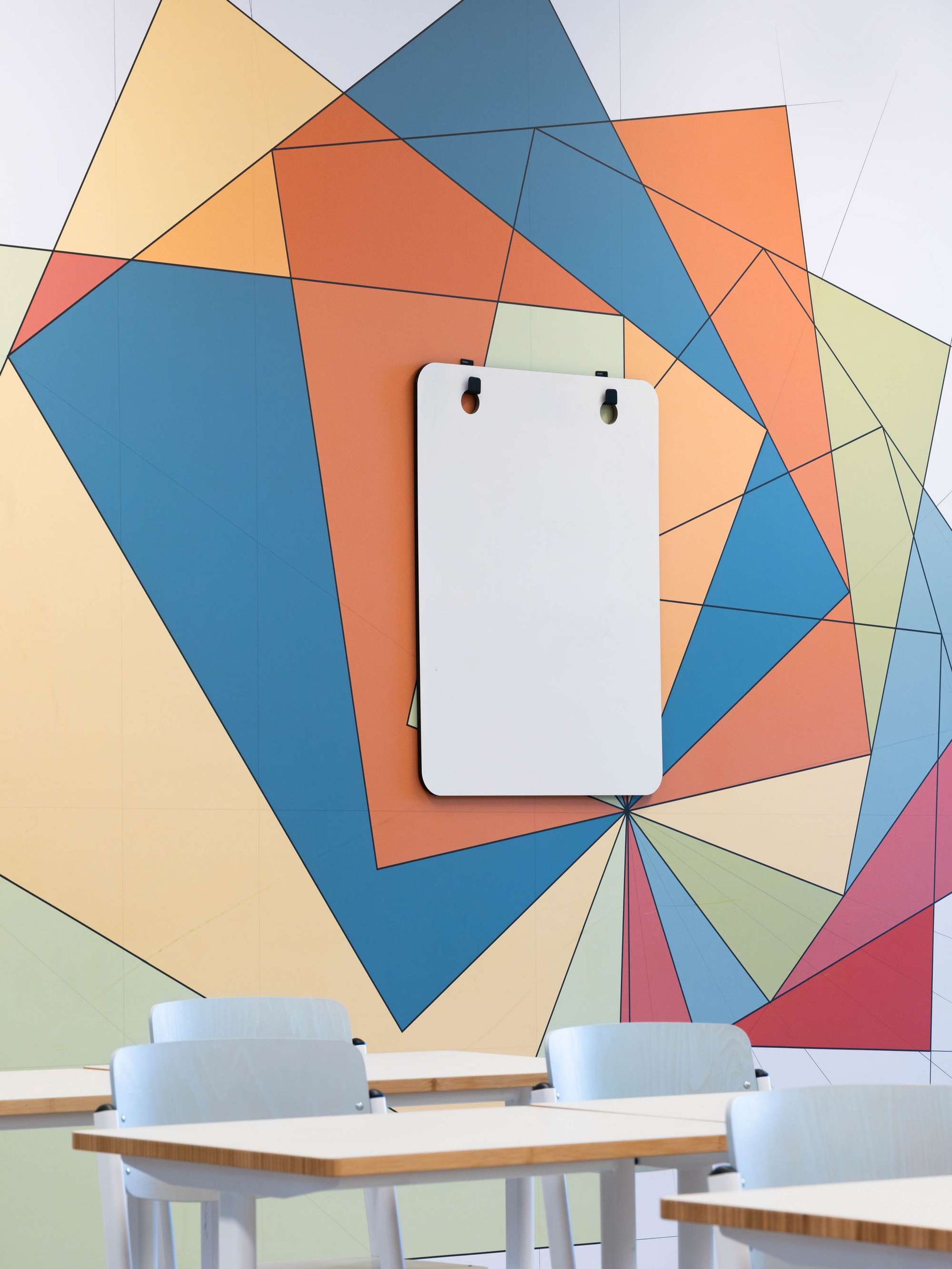 Een klaslokaal met tafels en stoelen en een whiteboard aan de muur