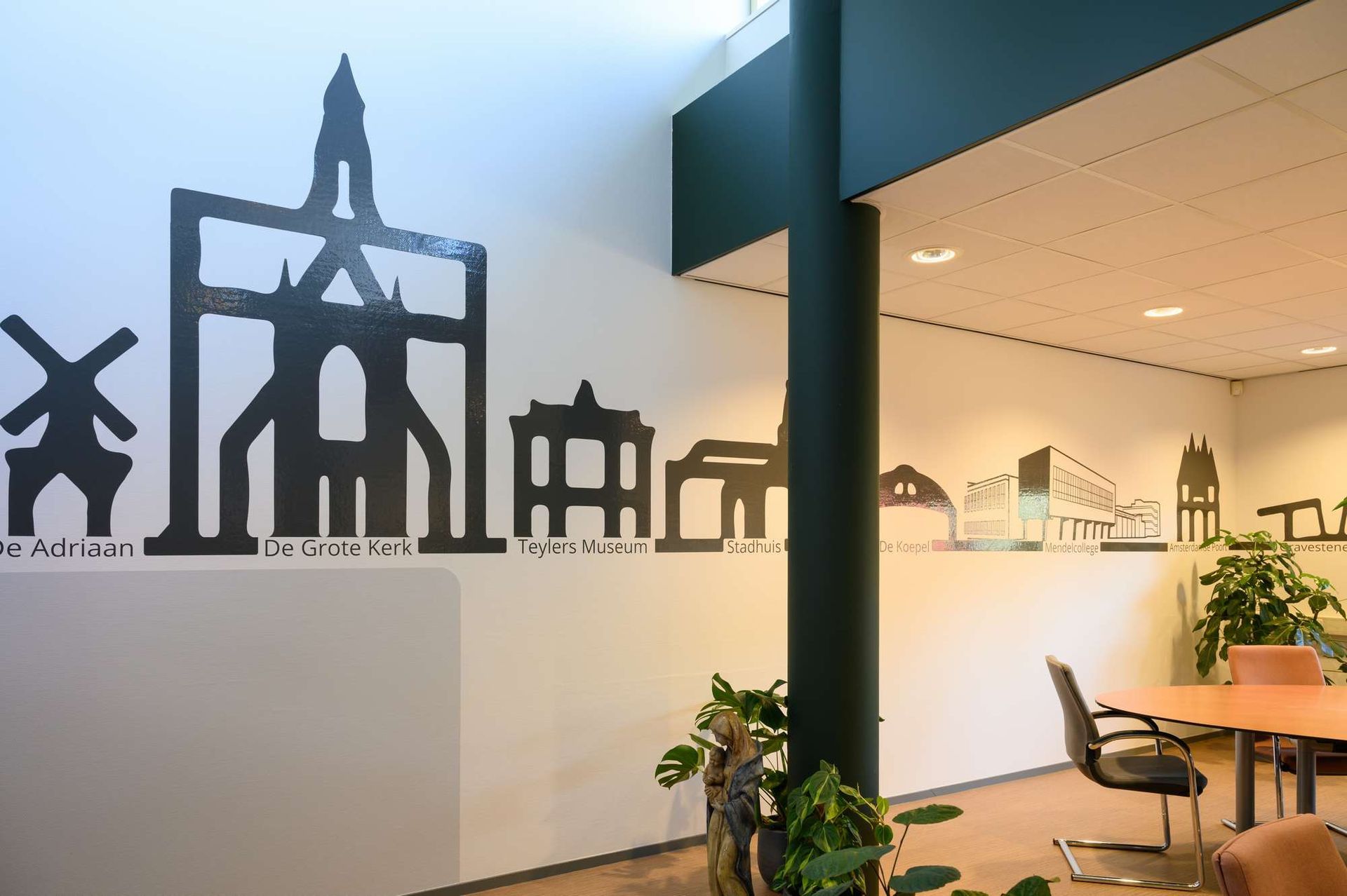 Een kamer met een tafel, stoelen en een silhouet van gebouwen op de muur.