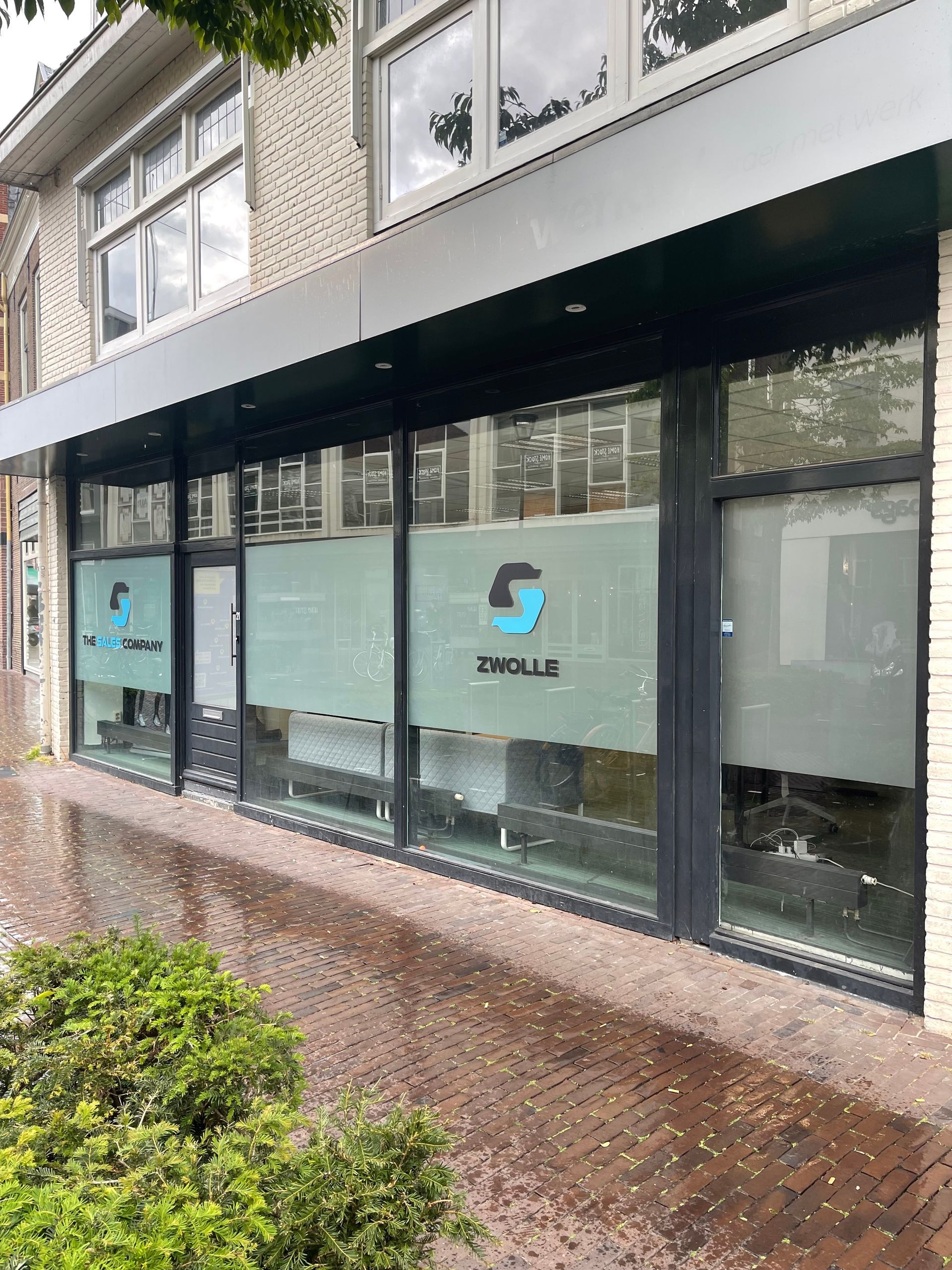 Een gebouw met veel ramen en een logo op de ramen.