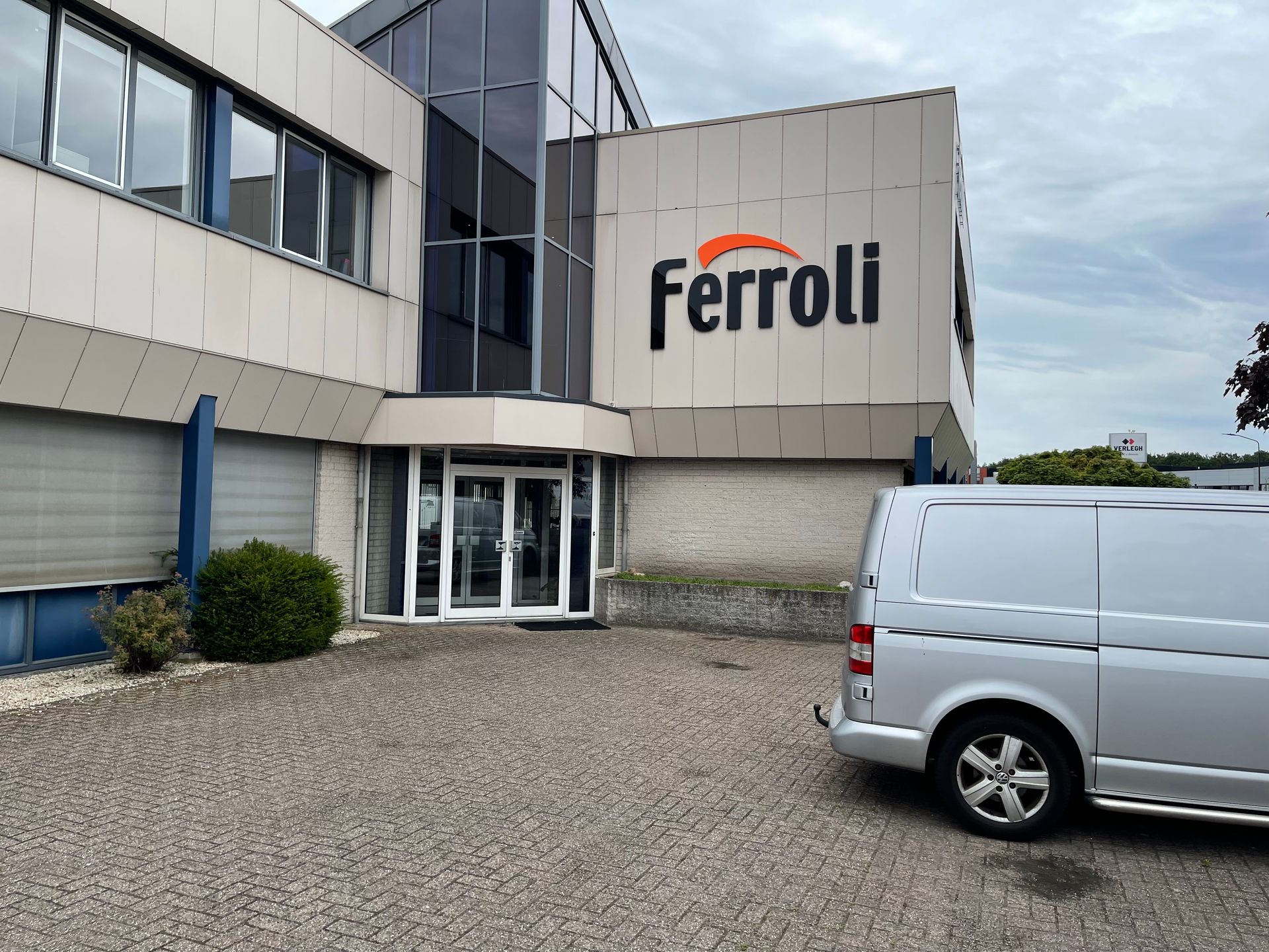 Een witte bestelwagen staat geparkeerd voor een gebouw met het opschrift ferroli
