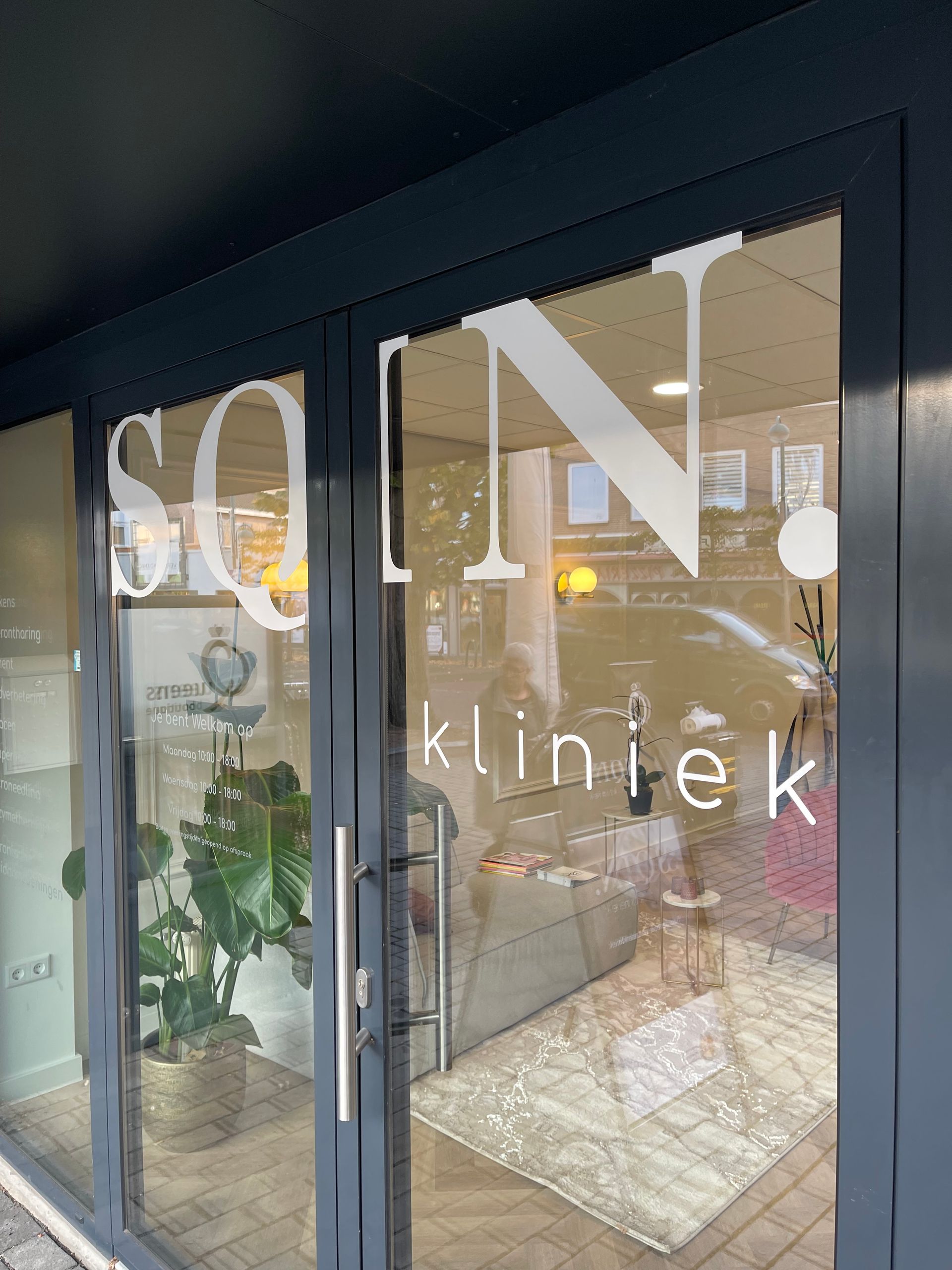 Een glazen deur met een bordje erop waarop staat 'soin kliniek'