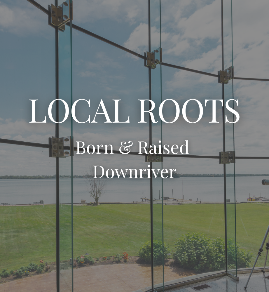 Local Roots sign in front of a grassy field and glass wall, with cloudy sky behind it