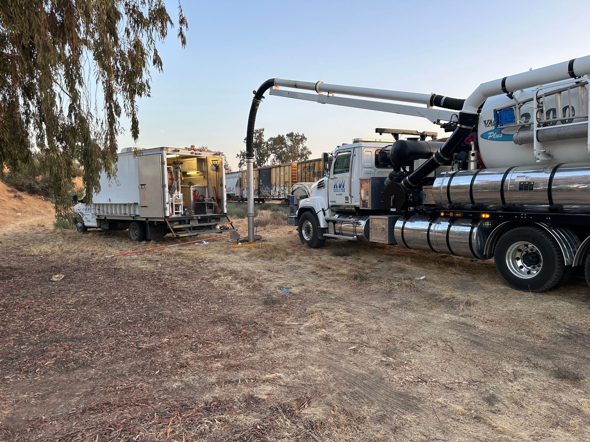 Two KVI Hydro Vac trucks are parked next to each other in a field.