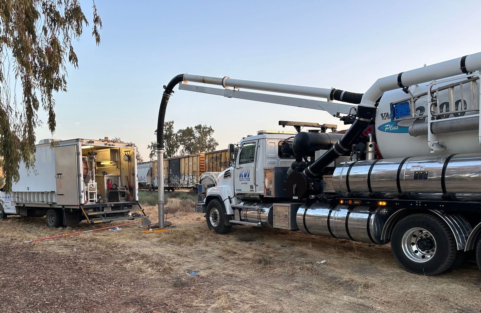 Two KVI Hydro Vac trucks are parked next to each other in a field.