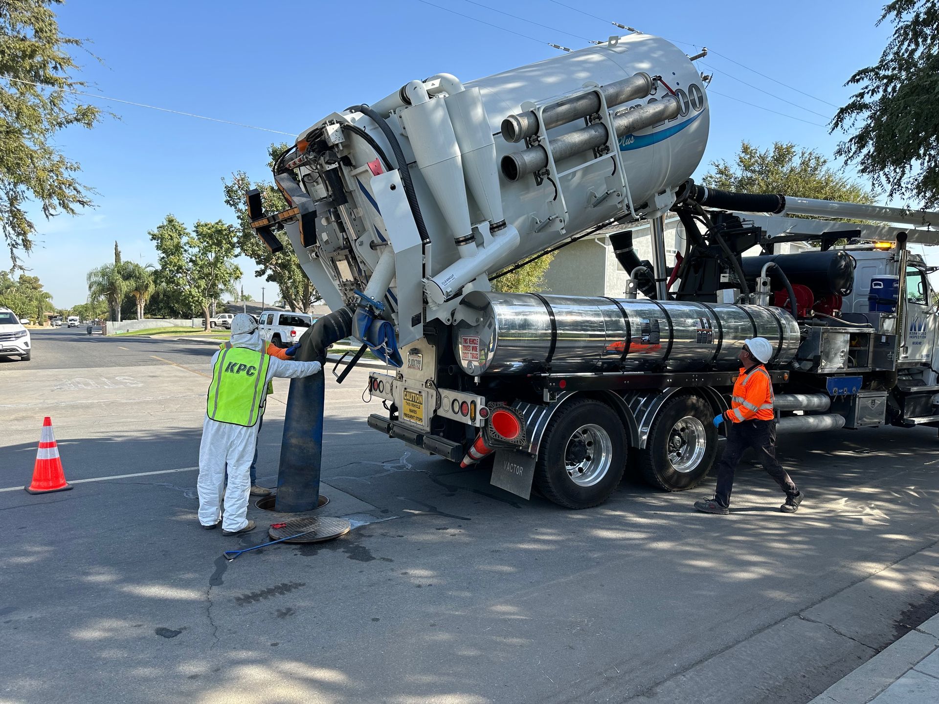 A man in a yellow saftey vest is standing next to a Hydro Vac truck.