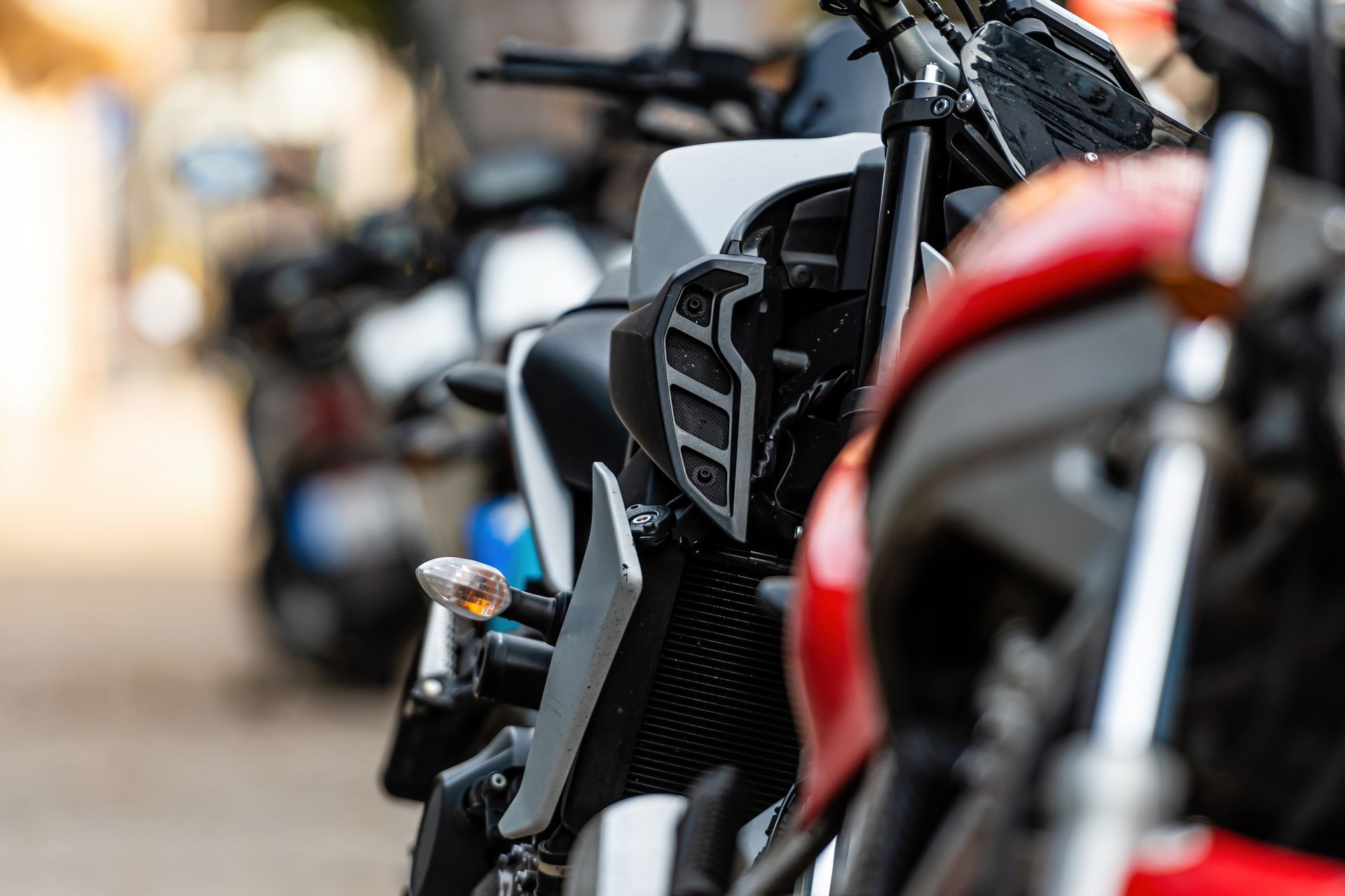 Close-up of parked motorcycles, with a black bike in sharp focus and a red bike blurred in the foreground