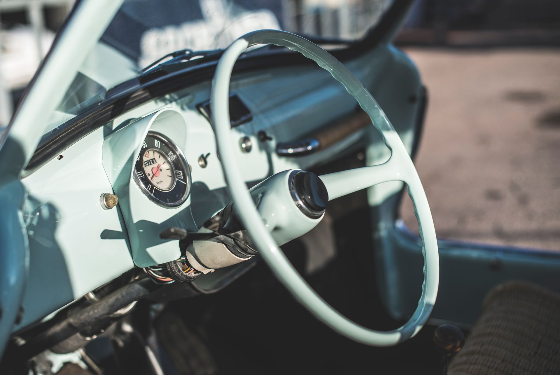Close-up of a vintage car dashboard and pale steering wheel in a sunlit interior