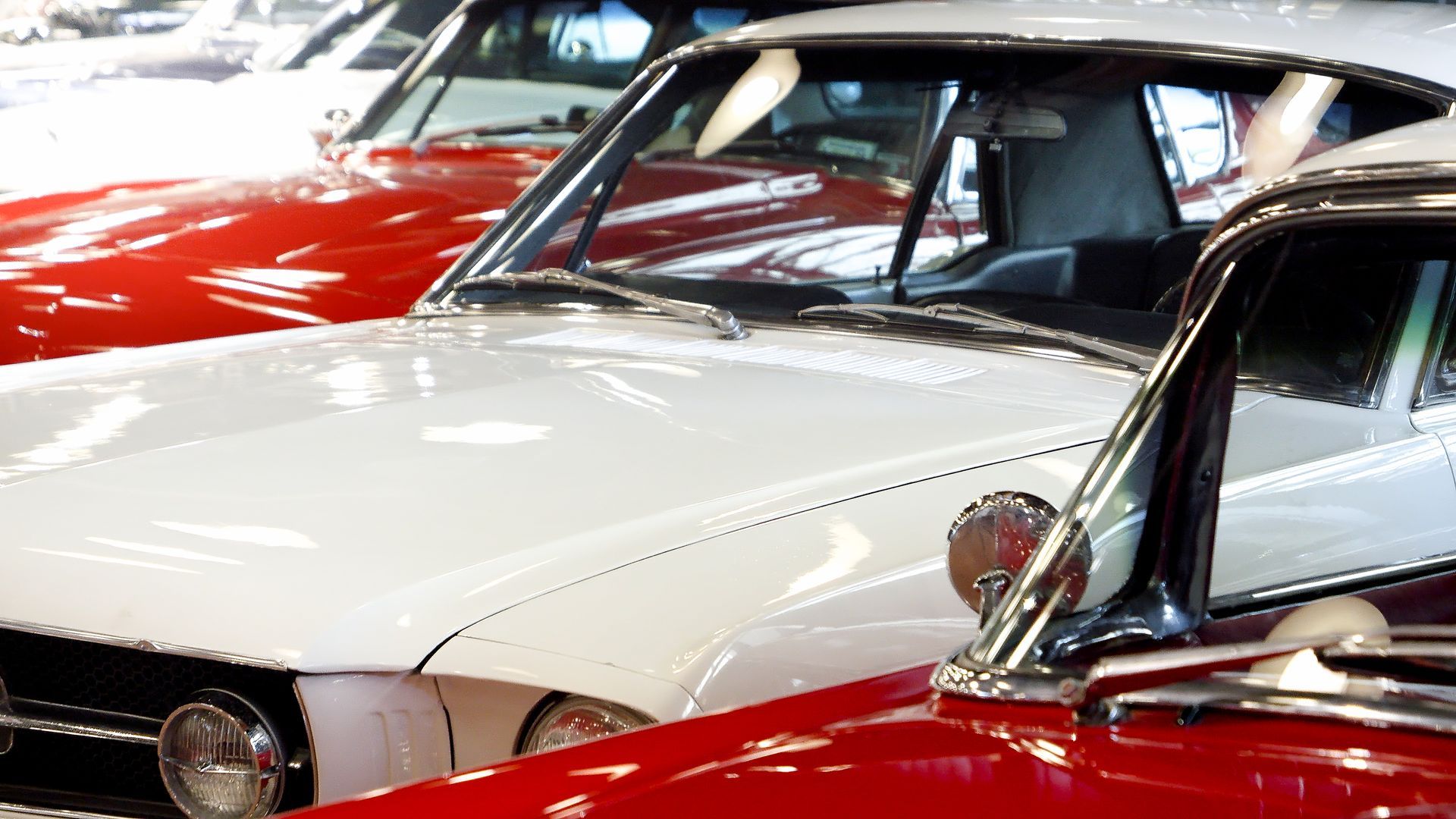 Classic red and white vintage cars parked closely together at a car show