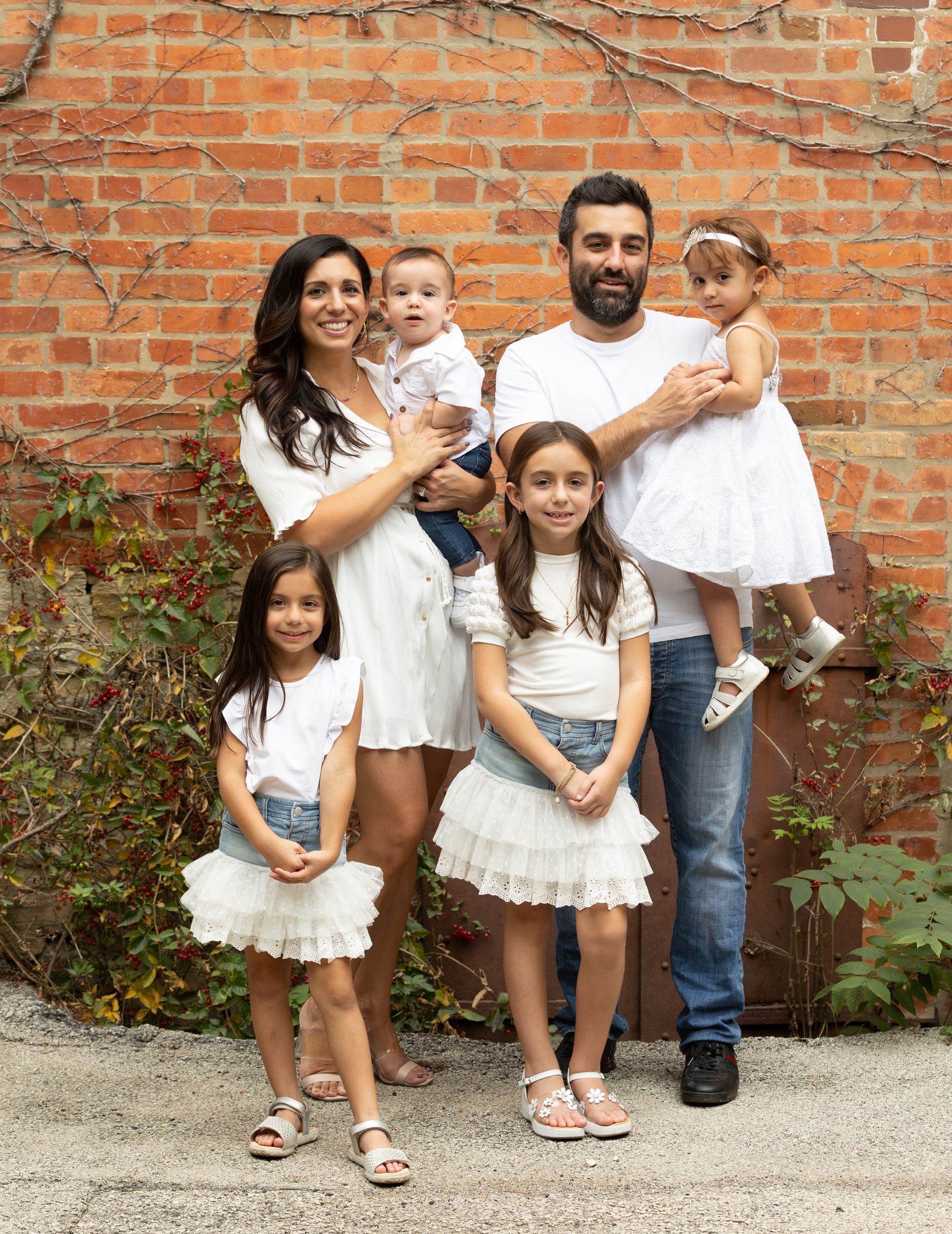 A family is posing for a picture in front of a brick wall.