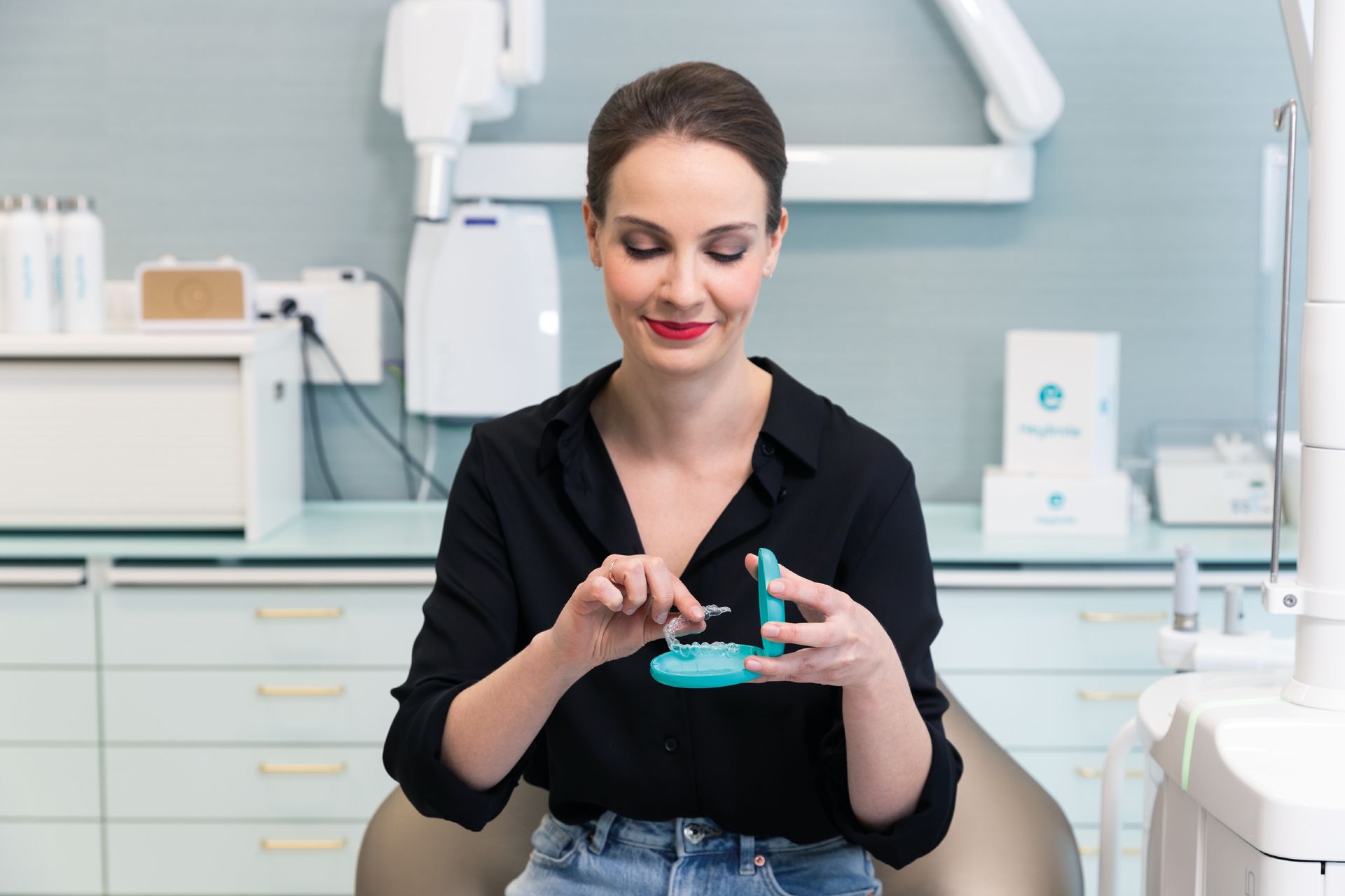 A woman is sitting in a dental chair holding a dental model.