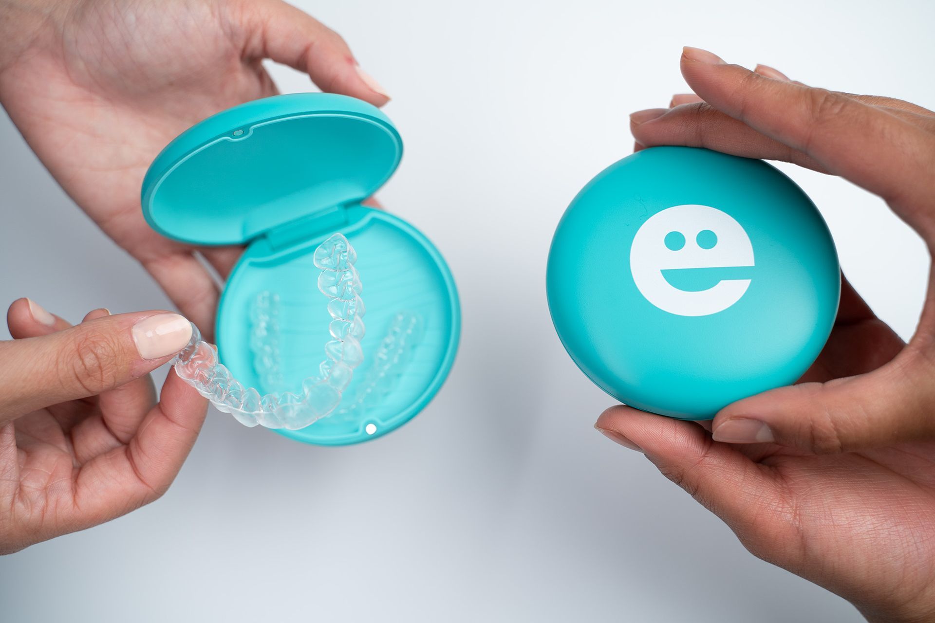 A person is holding a case with a smiley face on it.
