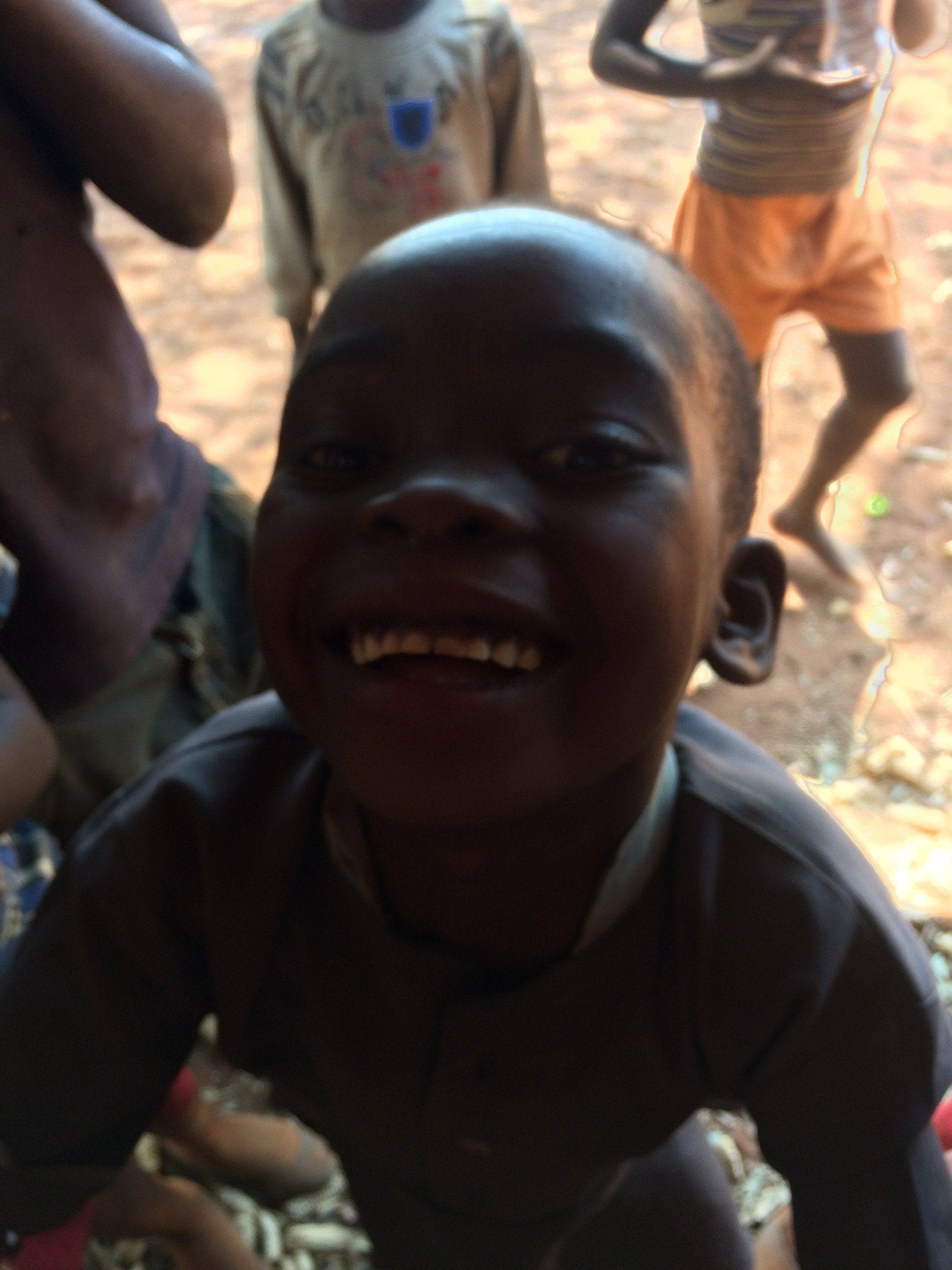 A young boy is smiling in front of a group of children