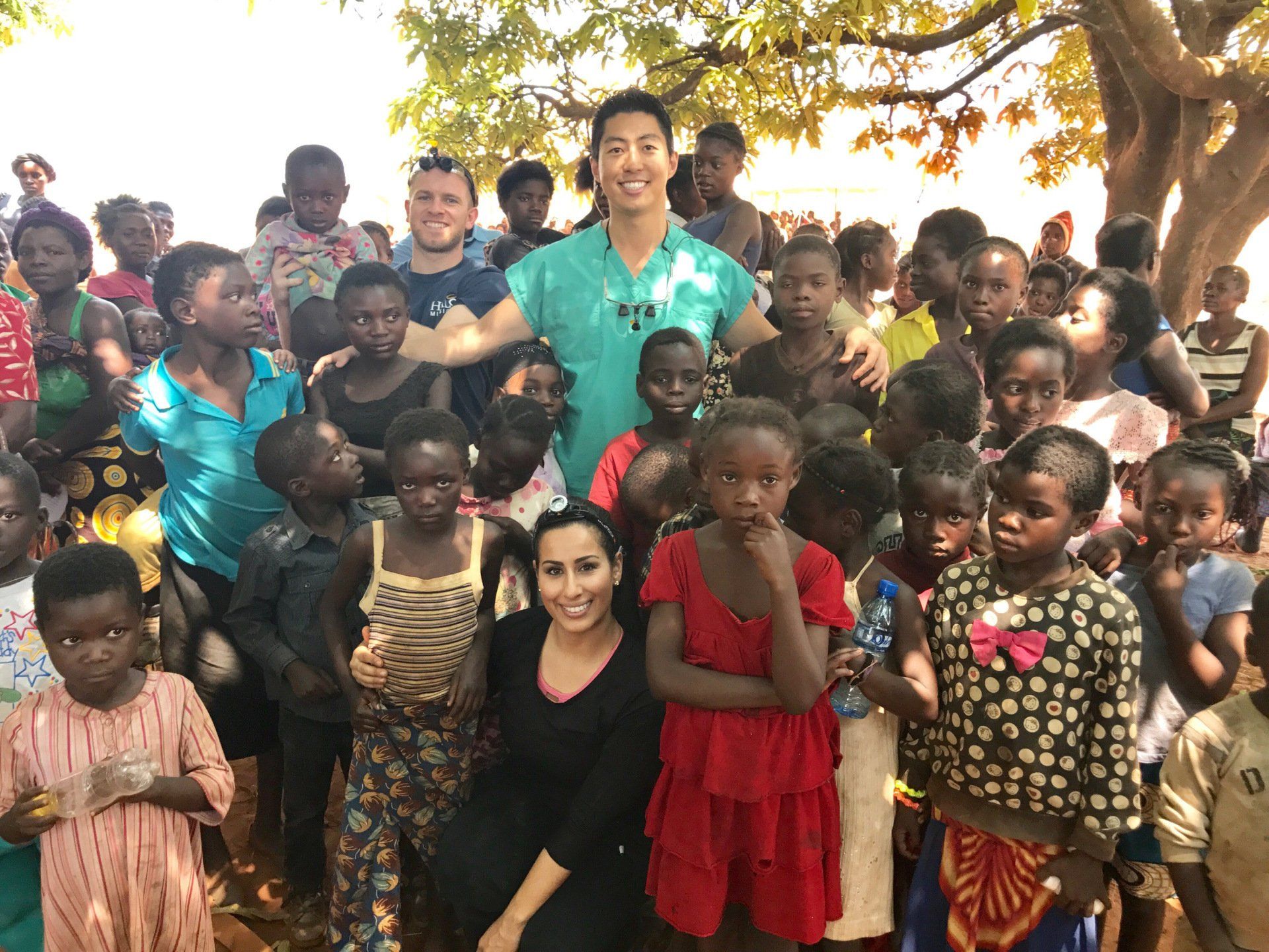 A man and a woman are posing for a picture with a group of children.