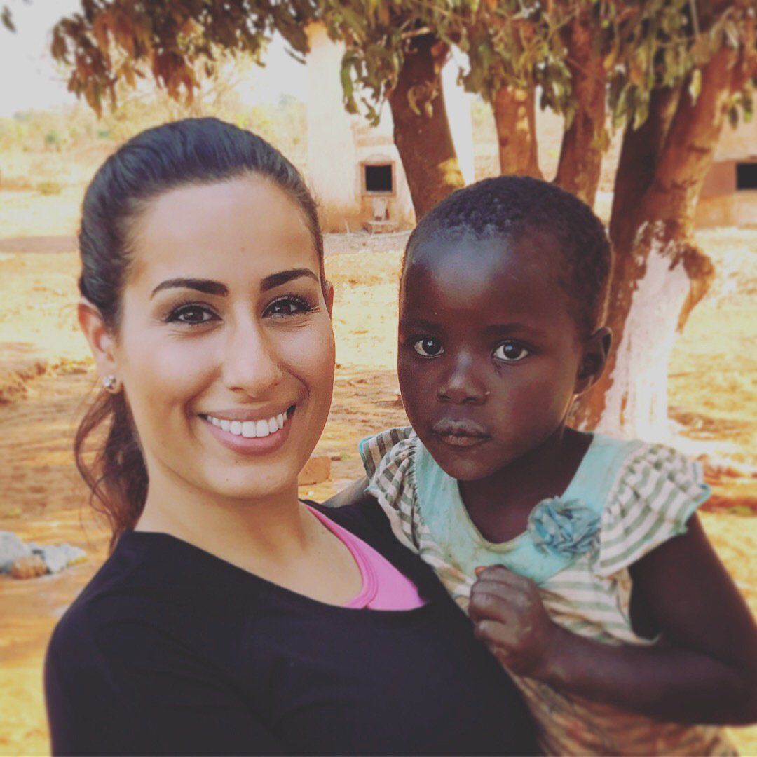 A woman is smiling while holding a little girl in her arms.