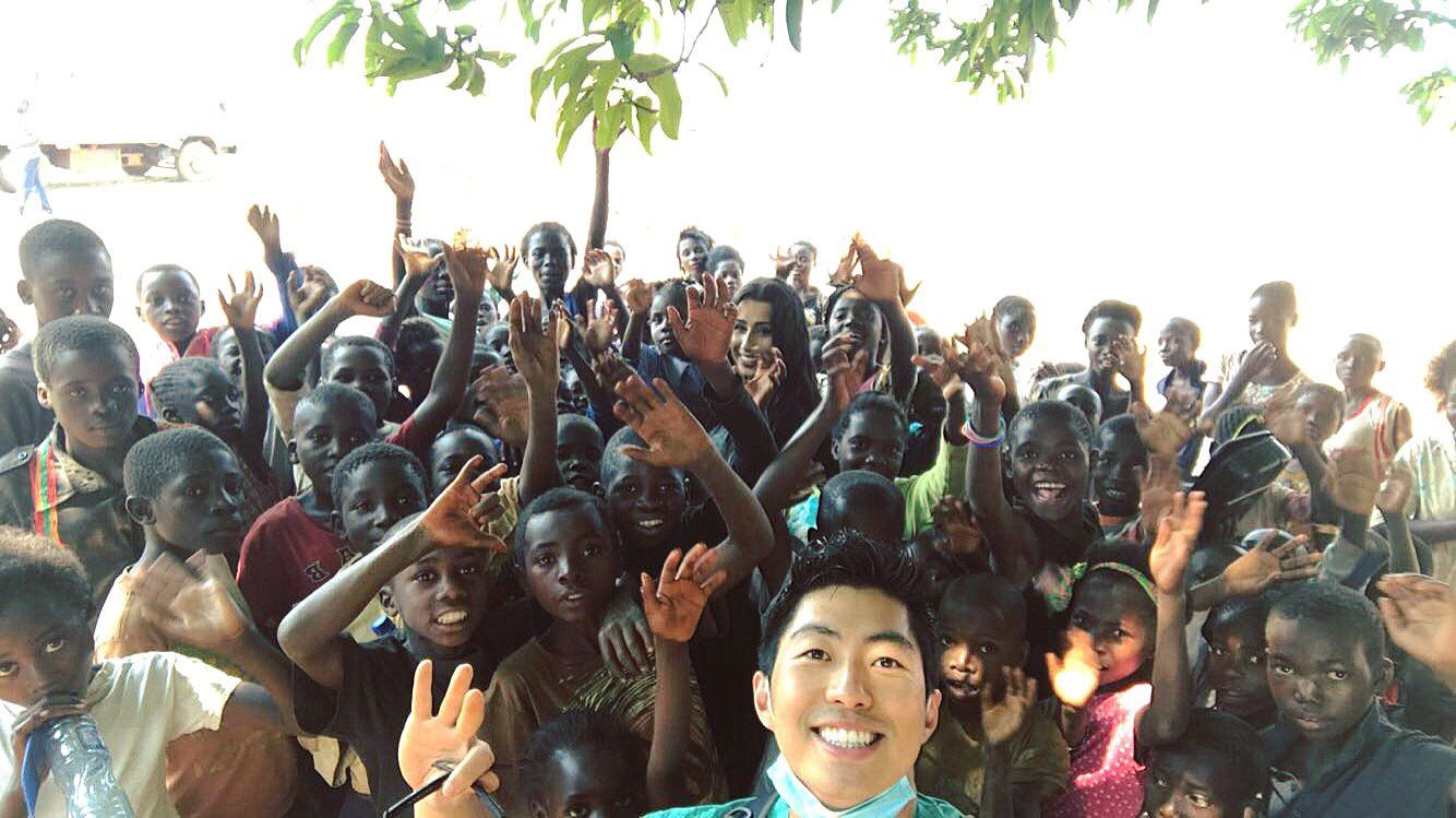 A man is taking a selfie with a group of children.
