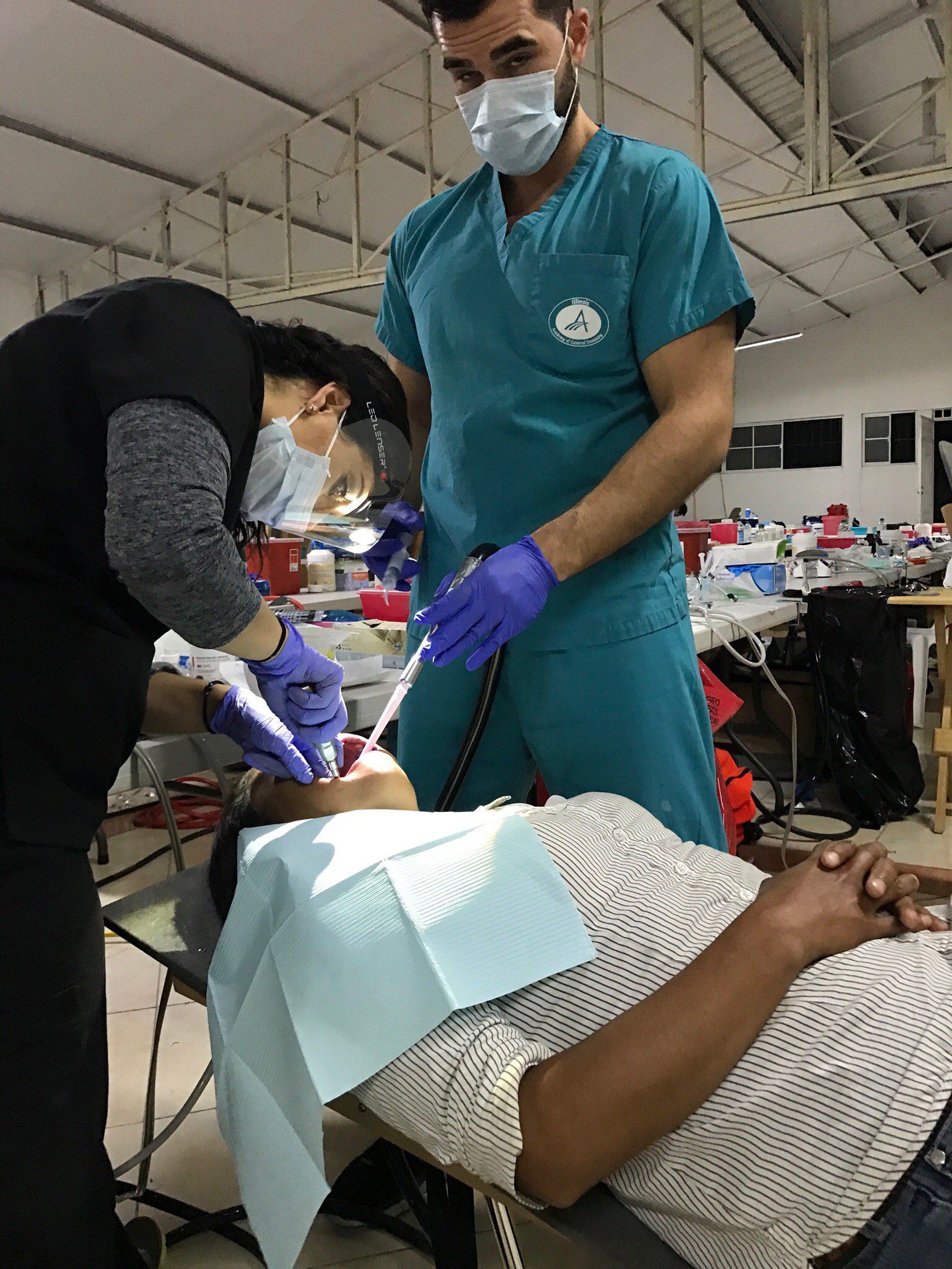 A man is getting his teeth examined by two dentists