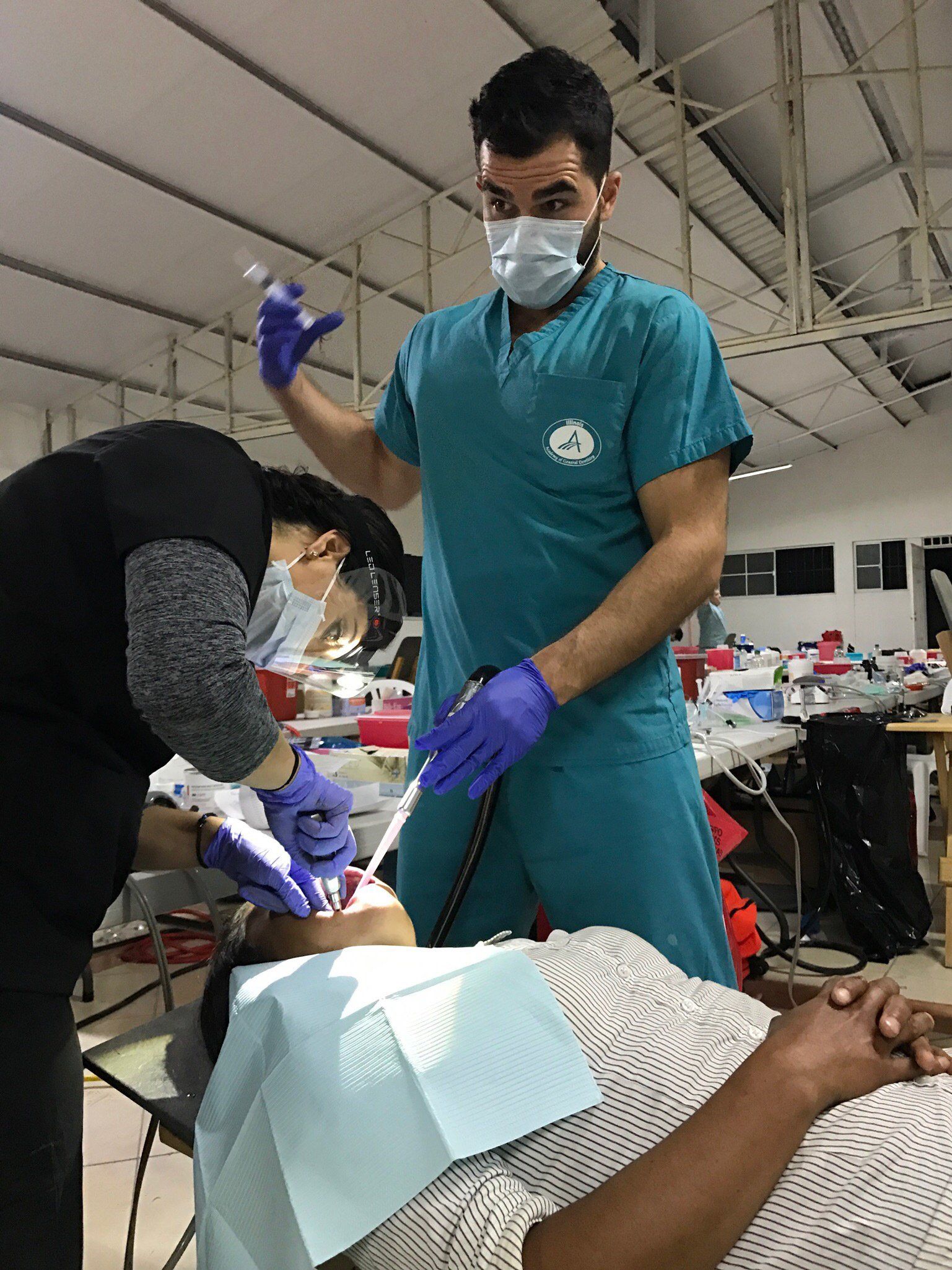 A man wearing a mask is working on a woman 's teeth