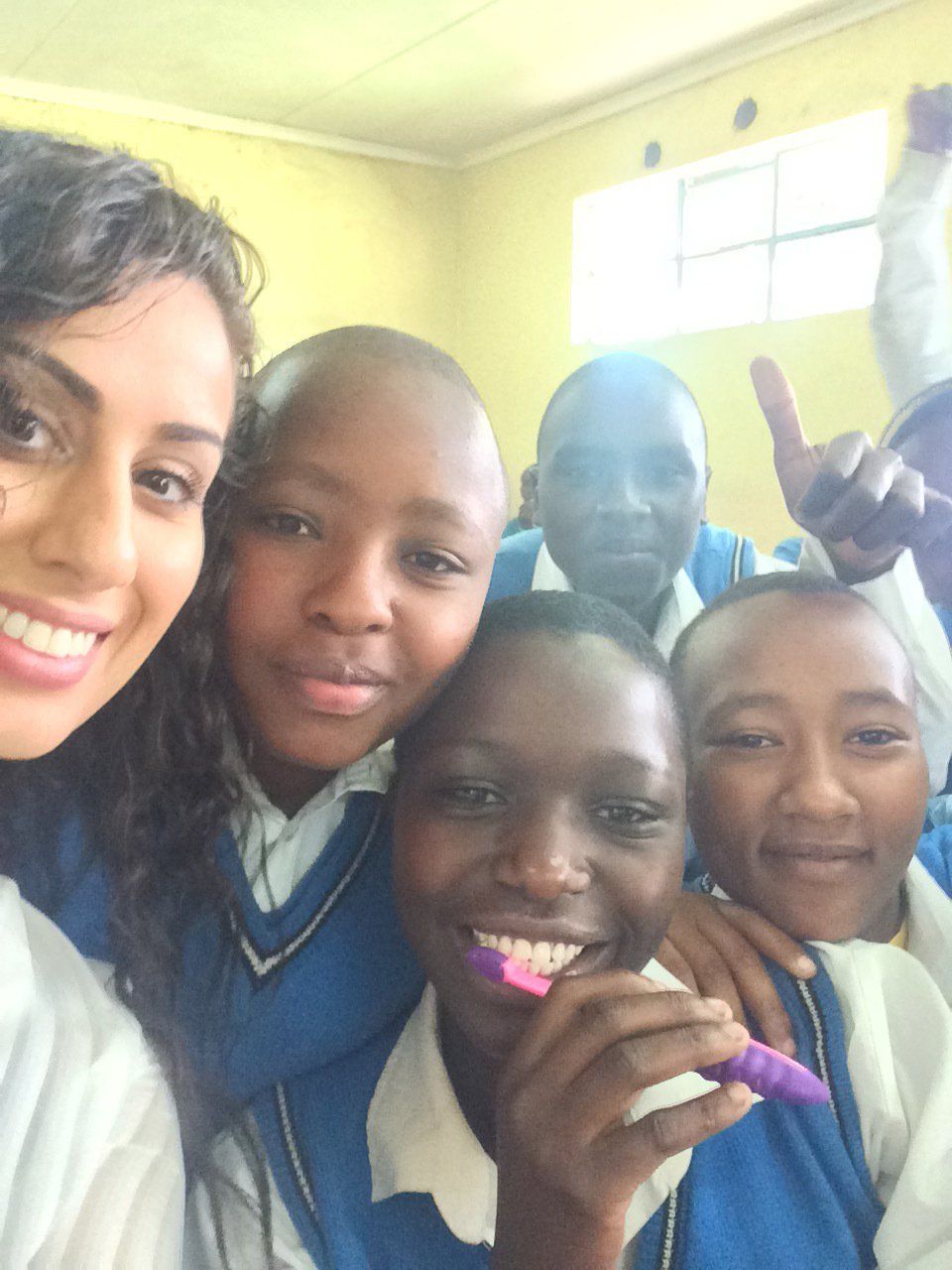 A group of children are posing for a picture and one of them is holding a toothbrush
