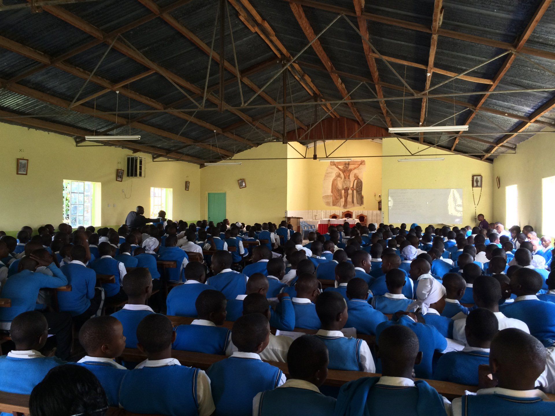 A large group of people in blue uniforms are sitting in a classroom