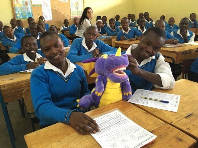 A group of students are sitting in a classroom with a stuffed animal