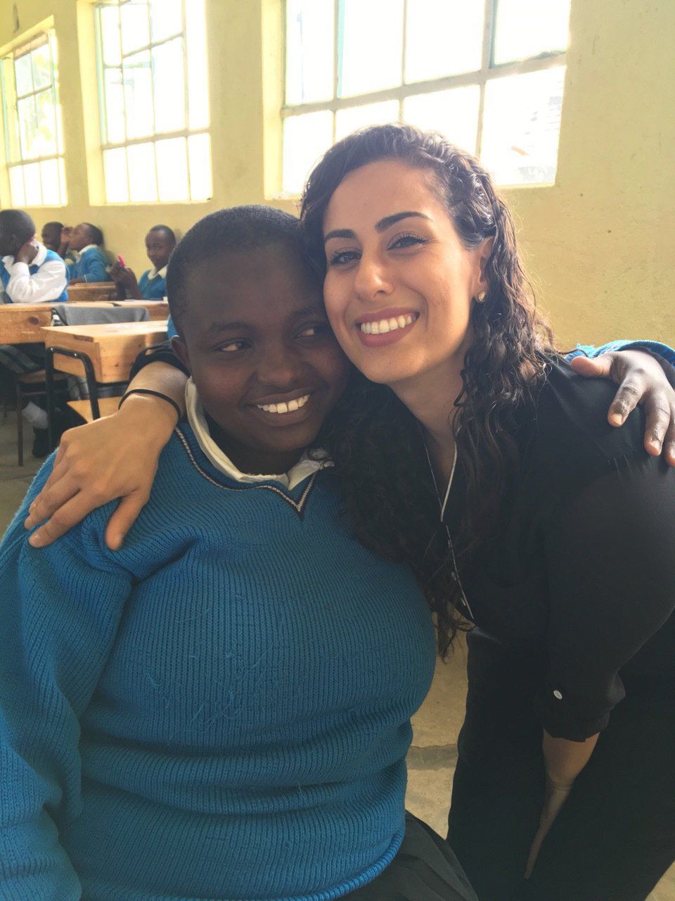 Two women posing for a picture with one wearing a blue sweater