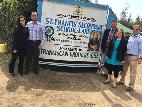 A group of people standing in front of a sign for st. francis secondary school
