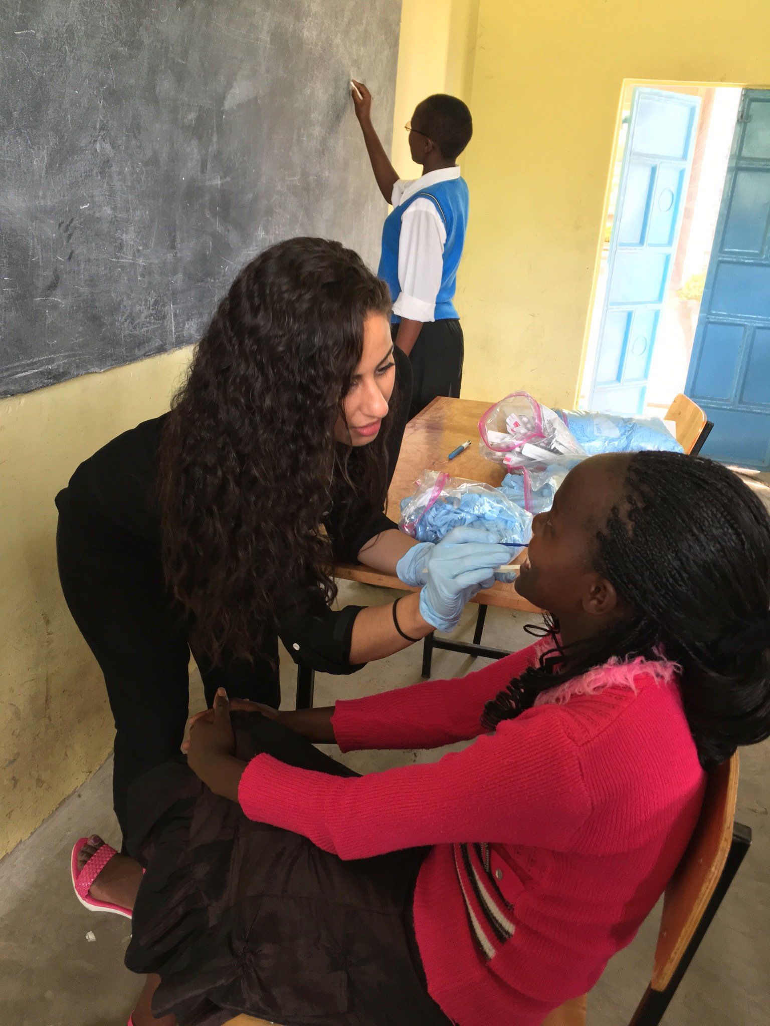 A girl in a pink sweater is being helped by a woman in a black shirt