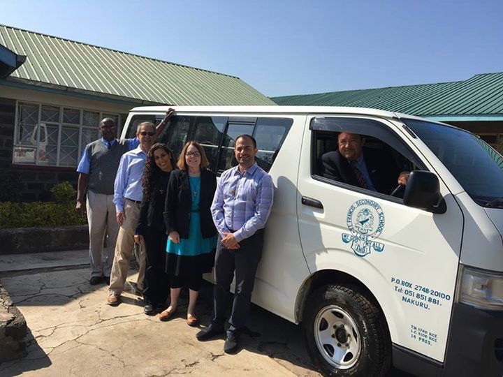 A group of people are standing in front of a white van.