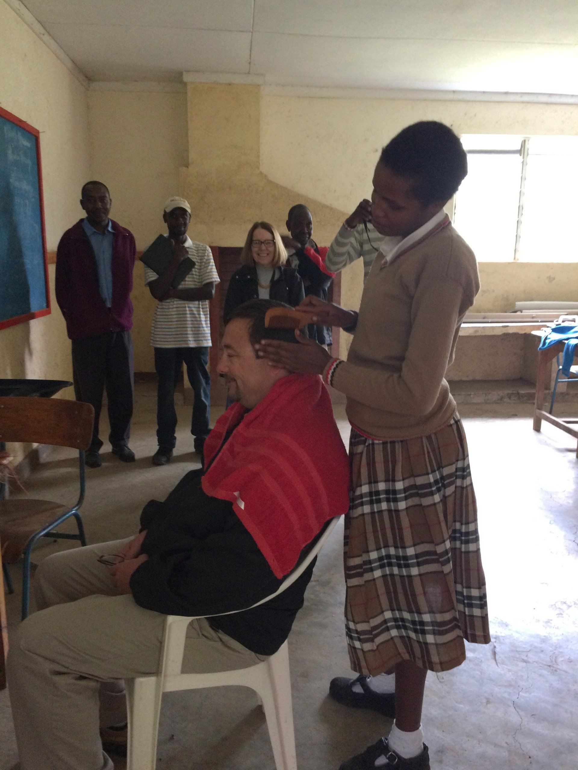 A woman in a plaid skirt is standing next to a man in a chair