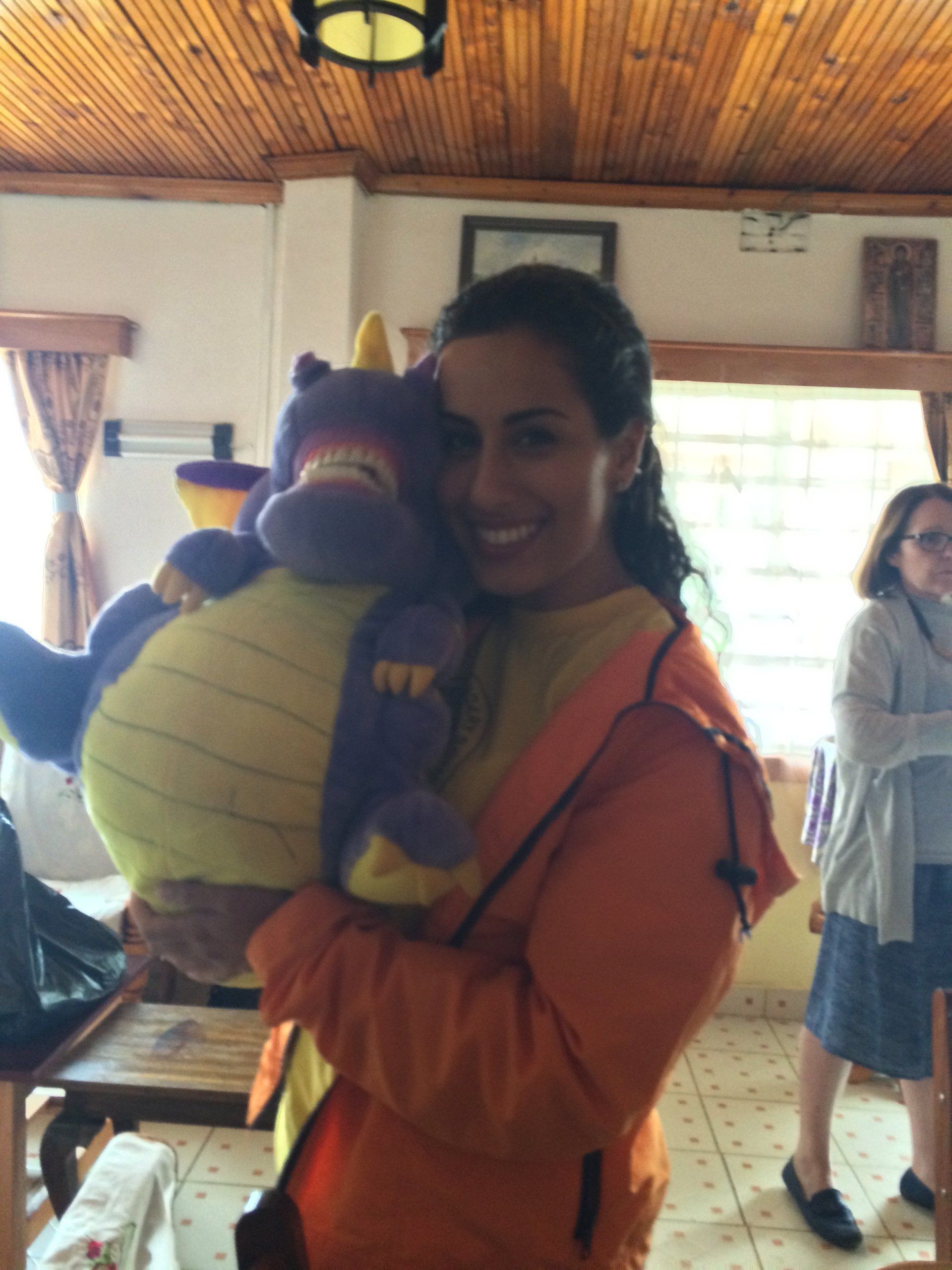 A woman in an orange jacket is holding a stuffed animal