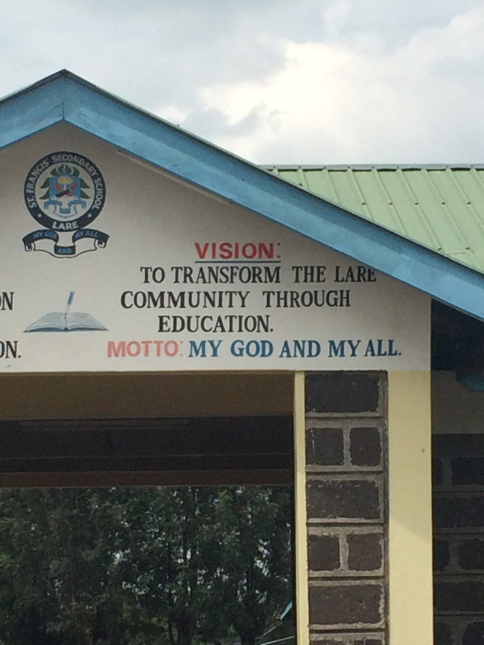 A sign that says vision to transform the lare community through education motto my god and my all
