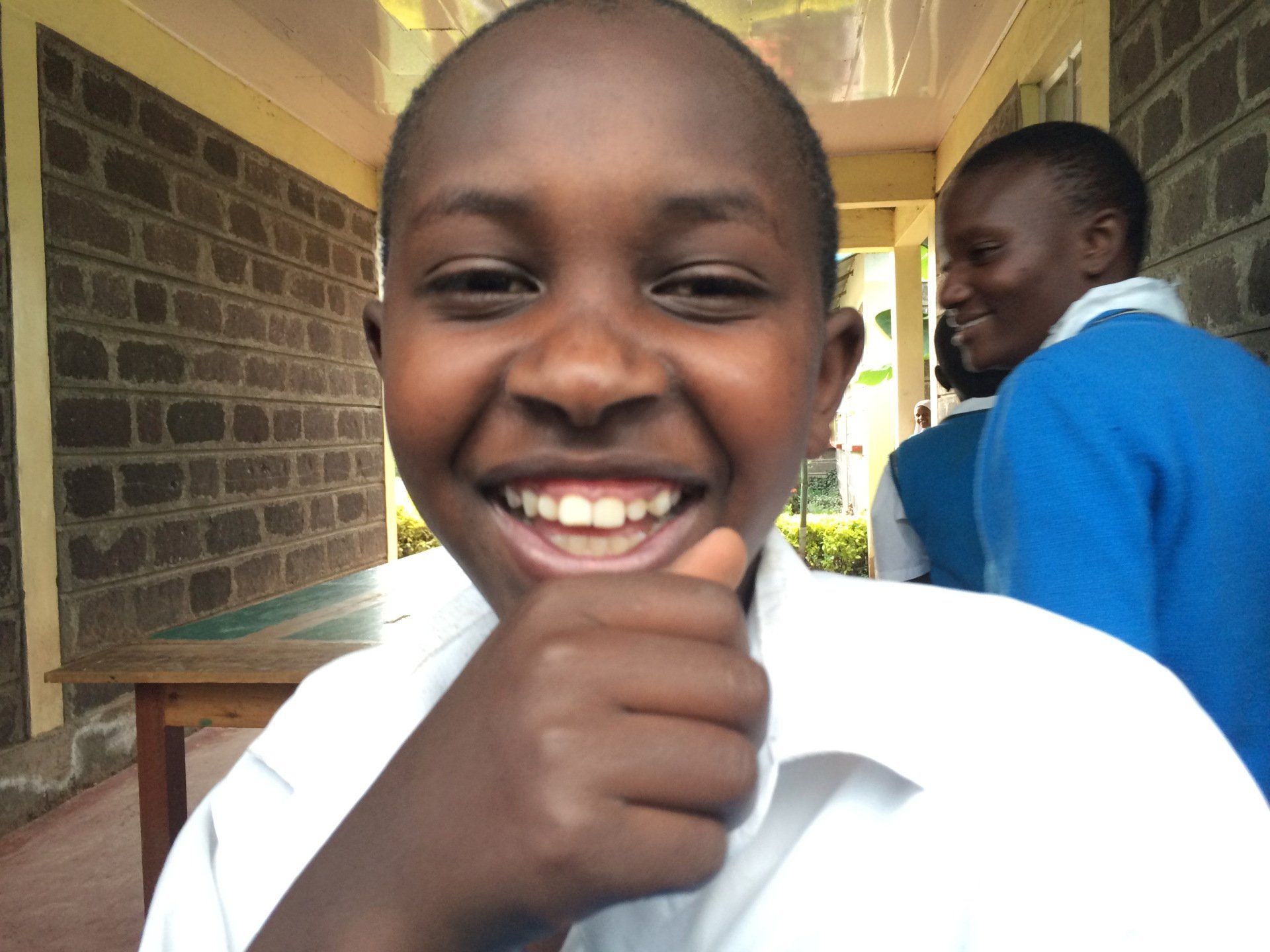 A young boy is smiling and giving a thumbs up